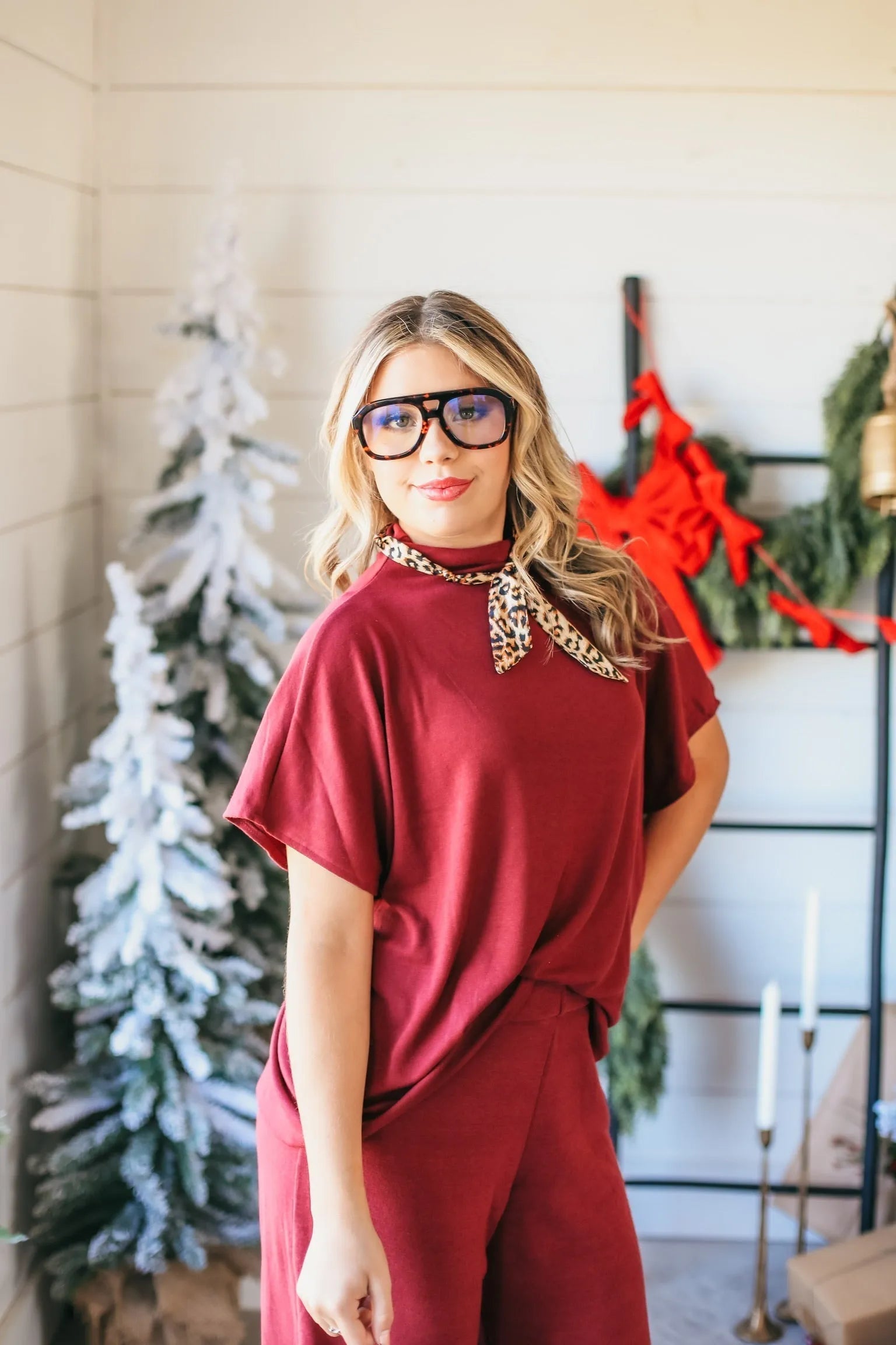 Burgundy ribbed matching set featuring a mock neck top and wide-leg pants. Model wears leopard print scarf and tortoise