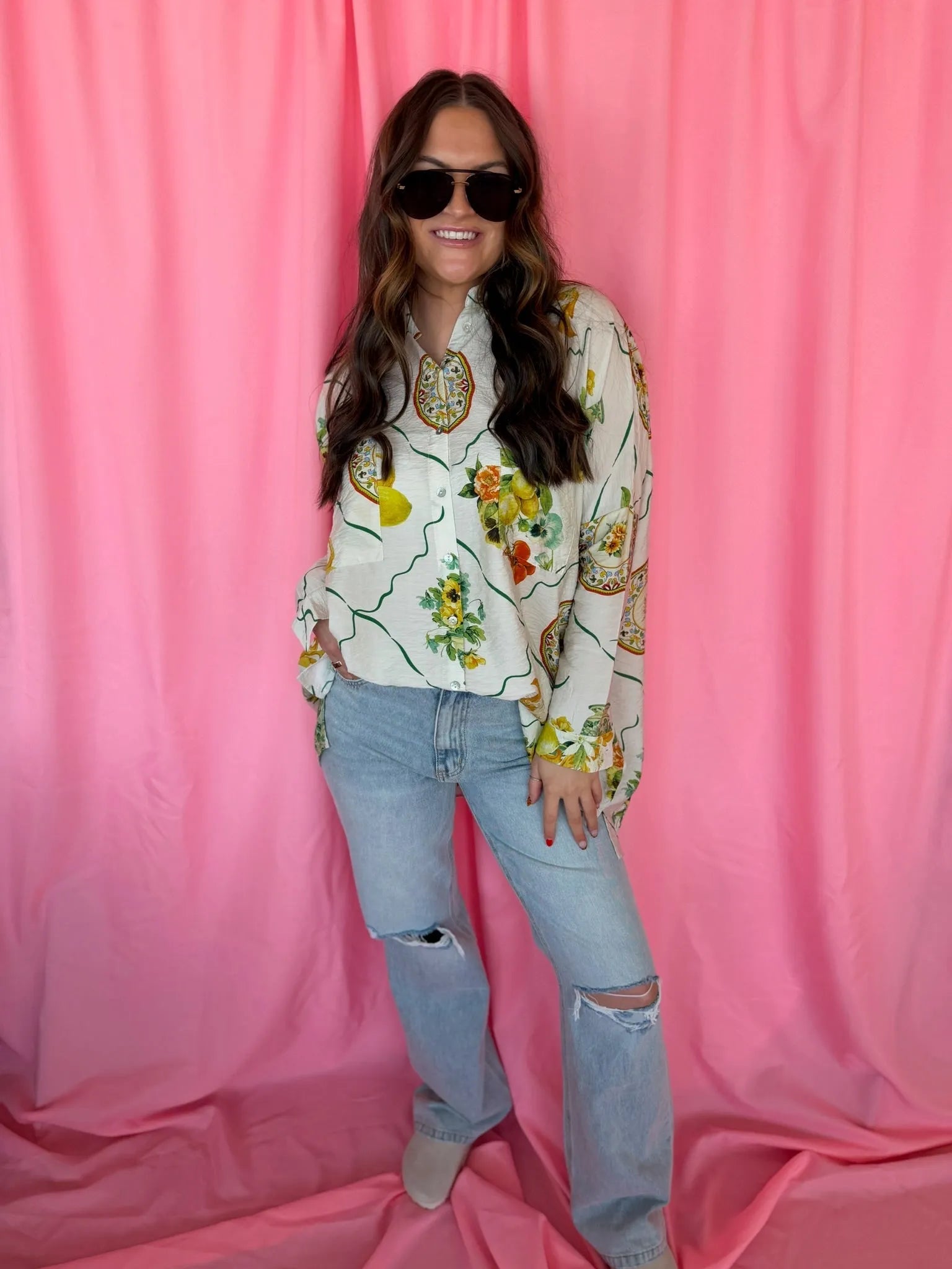 Entro Citrus Garden oversized button-down top with a colorful fruit and floral print, worn by a woman with sunglasses and