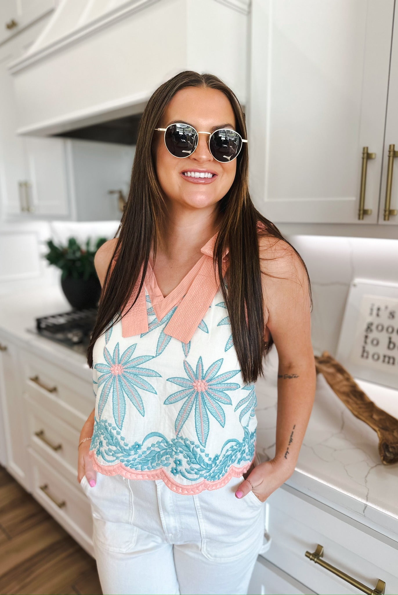 Entro embroidered white blouse with blue floral detail, peach collar, and scalloped hem. Model wears white pants and