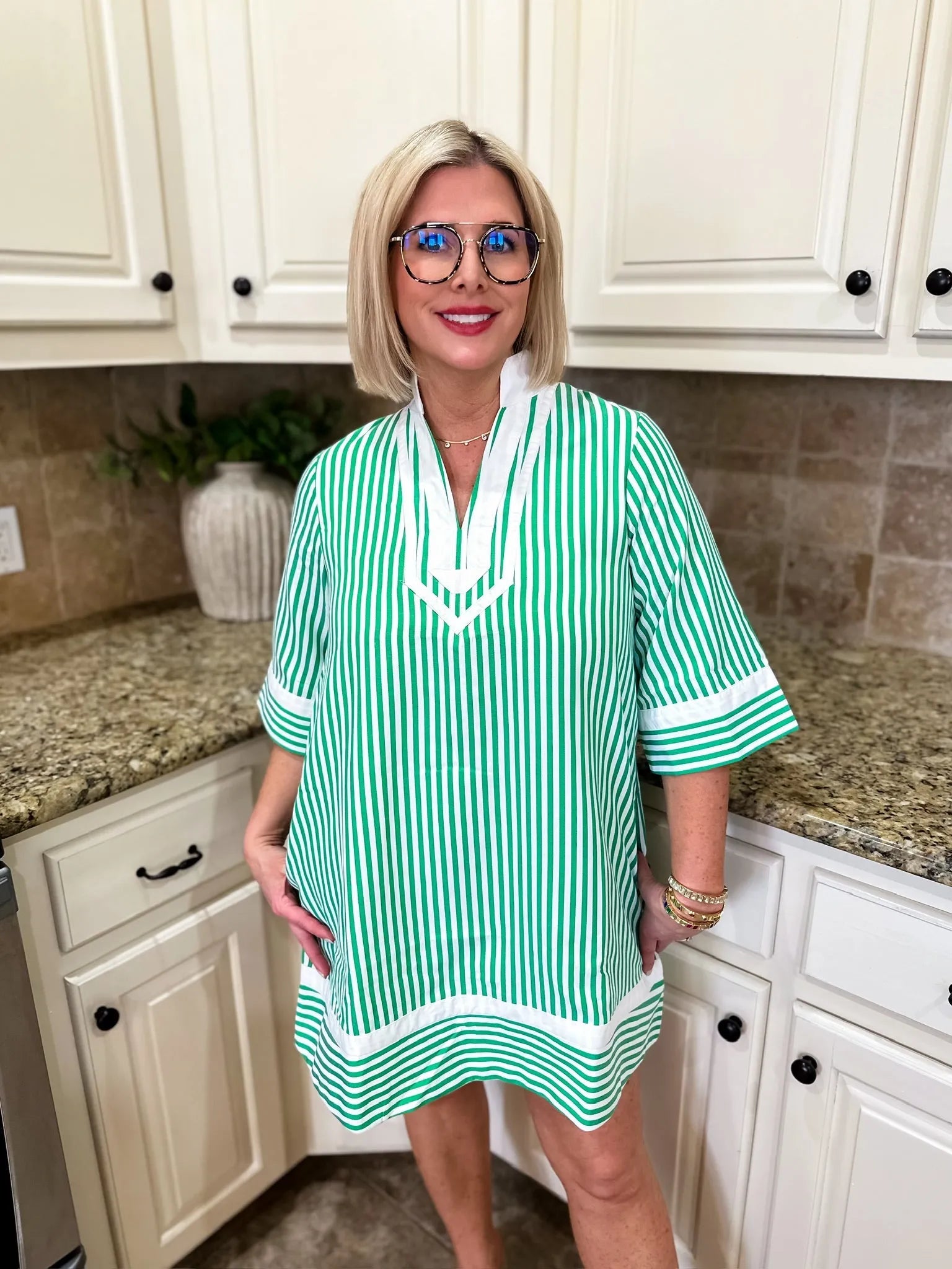 Entro green and white vertical stripe mini dress with V-neck and white trim on sleeves and hem. Woman wears glasses and