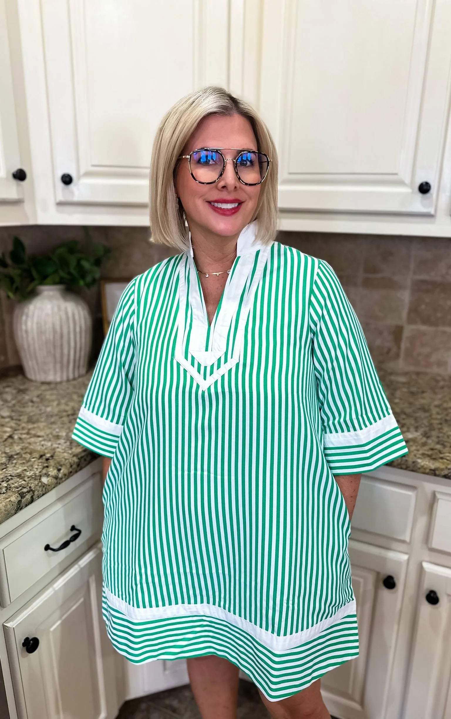 Woman wearing a green and white vertical stripe mini dress with a V-neck and white collar. The dress has short sleeves with