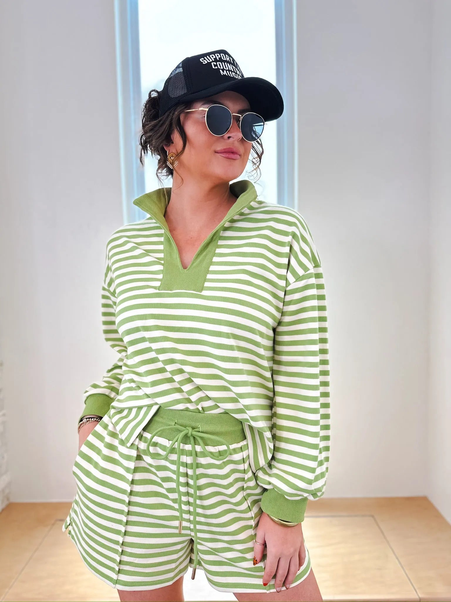 Woman wearing a green and white striped pullover top and matching shorts. The set has a collared neckline and drawstring
