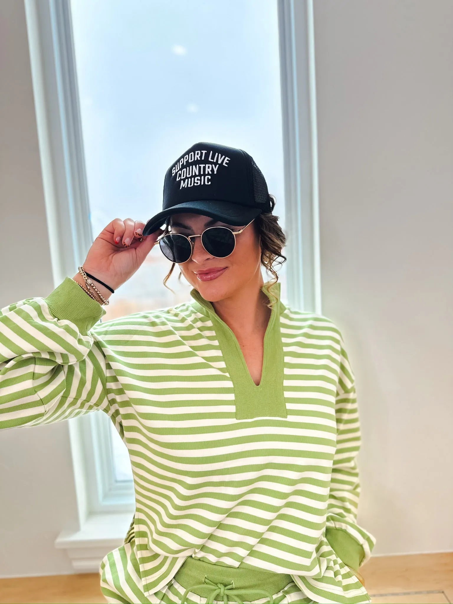 Green and cream striped pullover top with a v-neck and long sleeves.