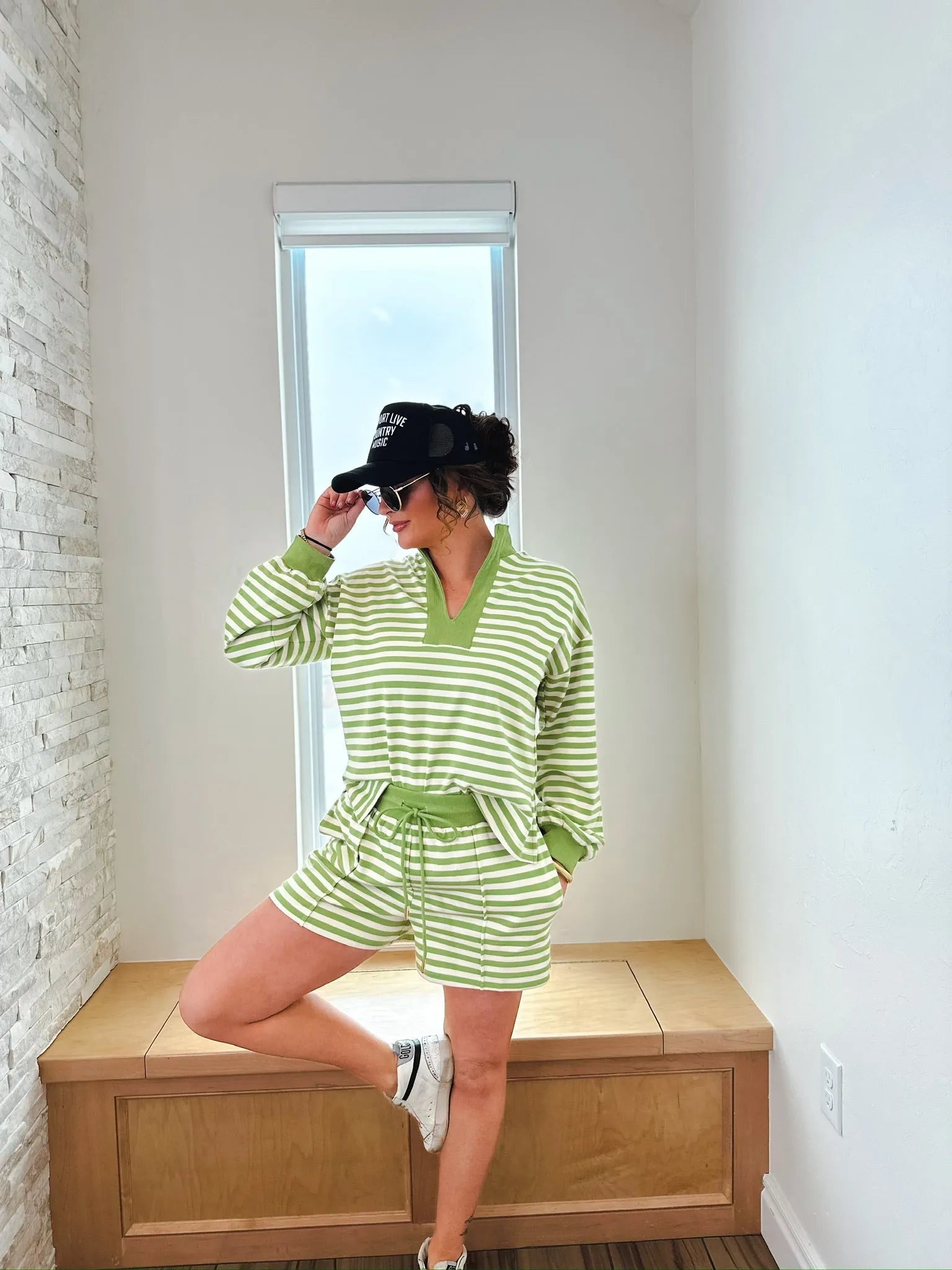 Woman wearing a green and white striped pullover top and matching shorts set. Features a V-neck collar and drawstring waist