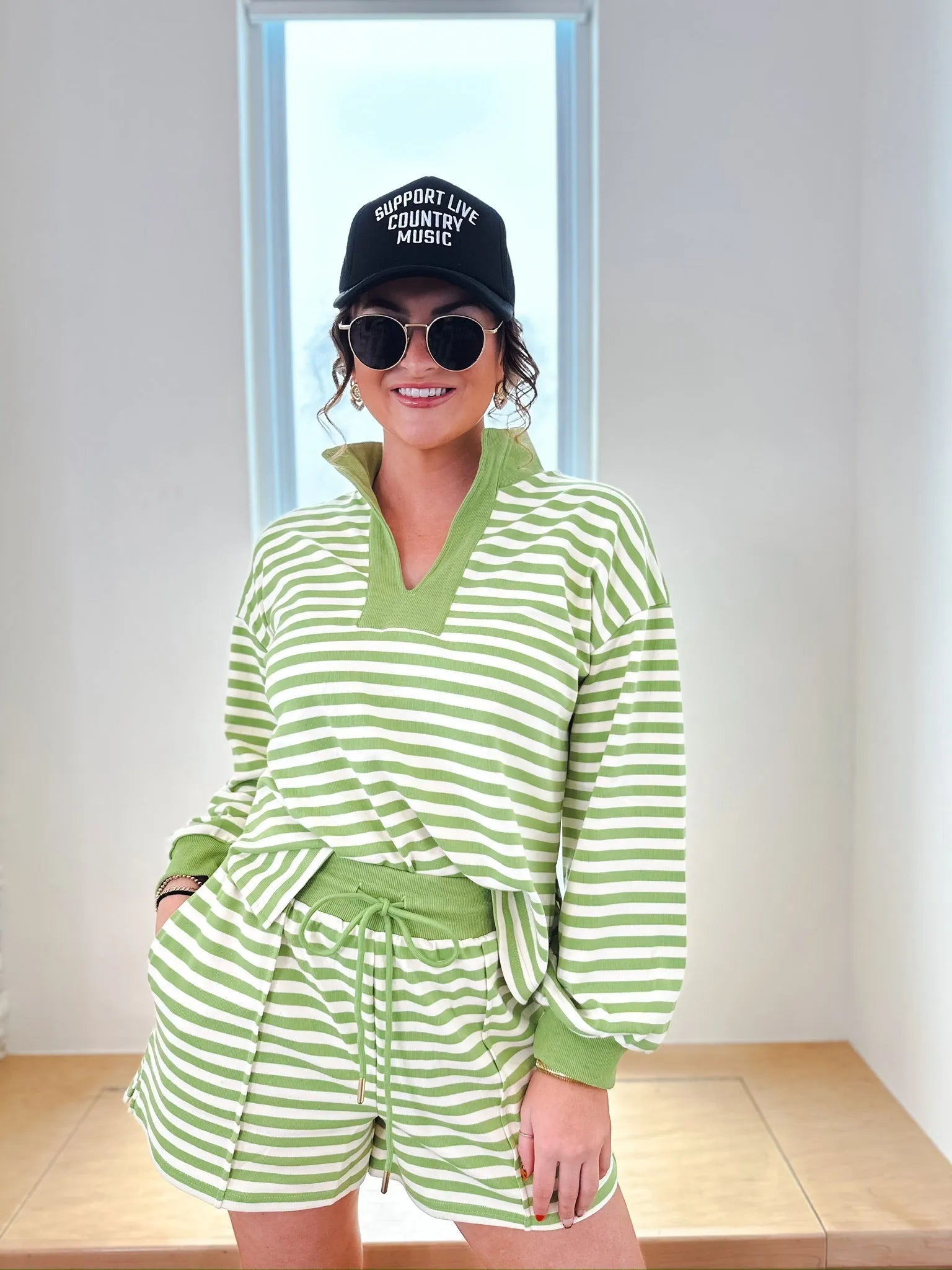 Green and white striped pullover and shorts set. Woman wearing a collared V-neck long-sleeve top with cuffed sleeves and