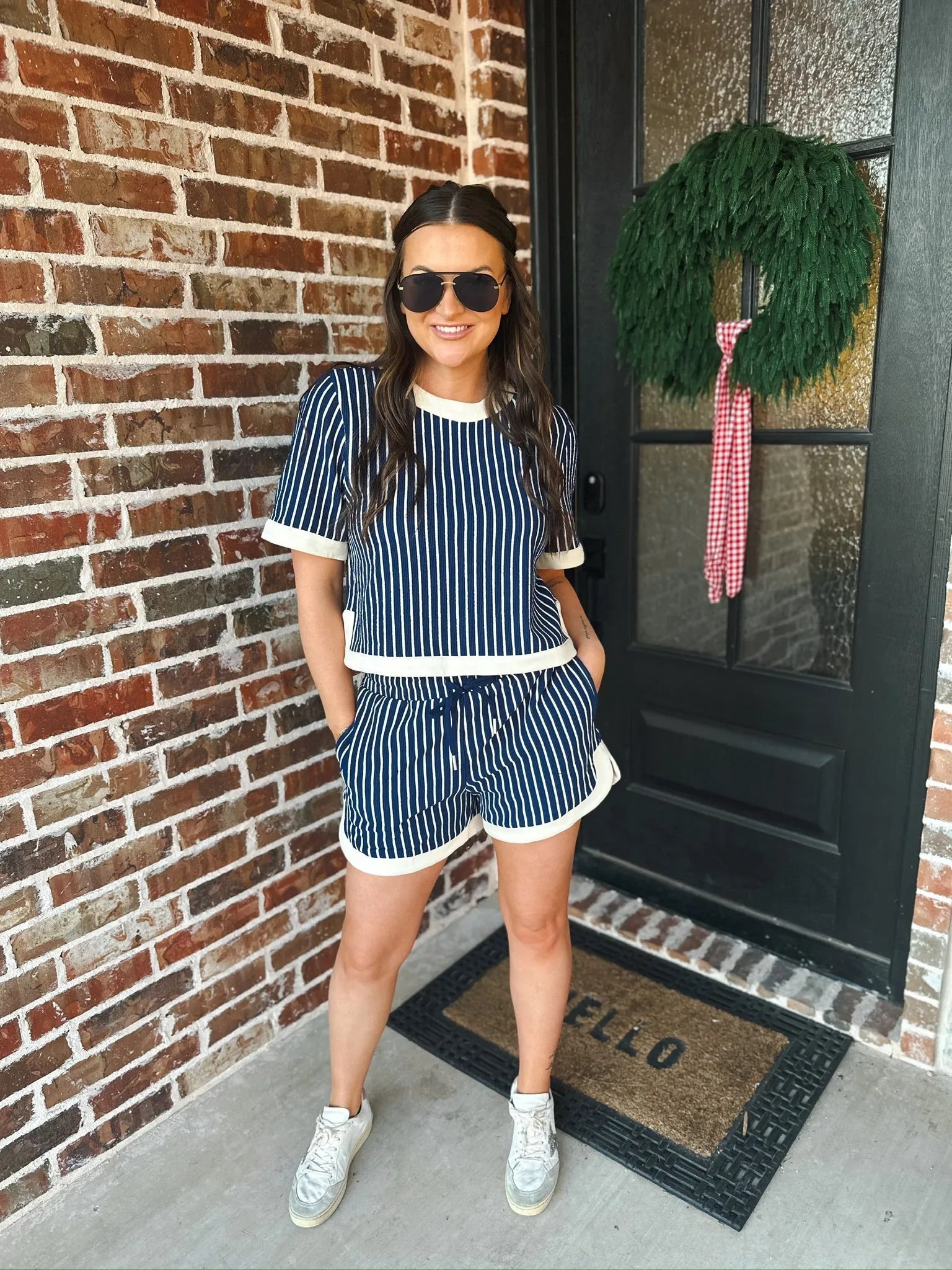 Woman wearing a navy and cream striped two-piece short set with cream trim and drawstring shorts.