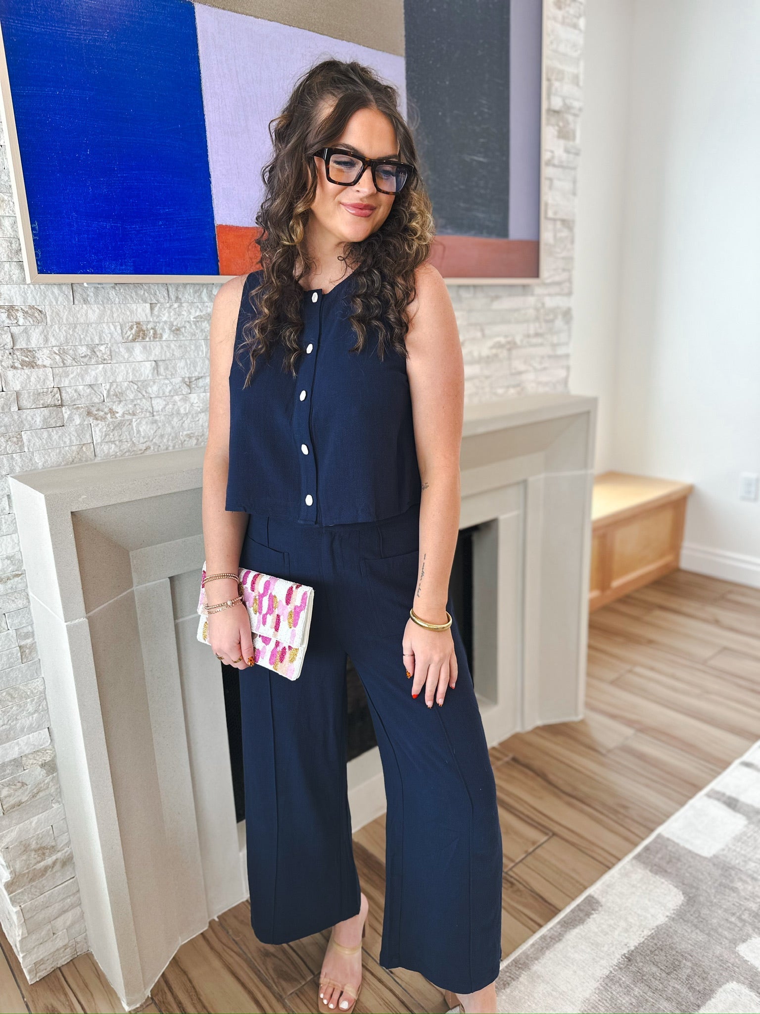 Entro navy sleeveless button-down blouse with white buttons, paired with matching navy wide-leg pants. Woman holds a small