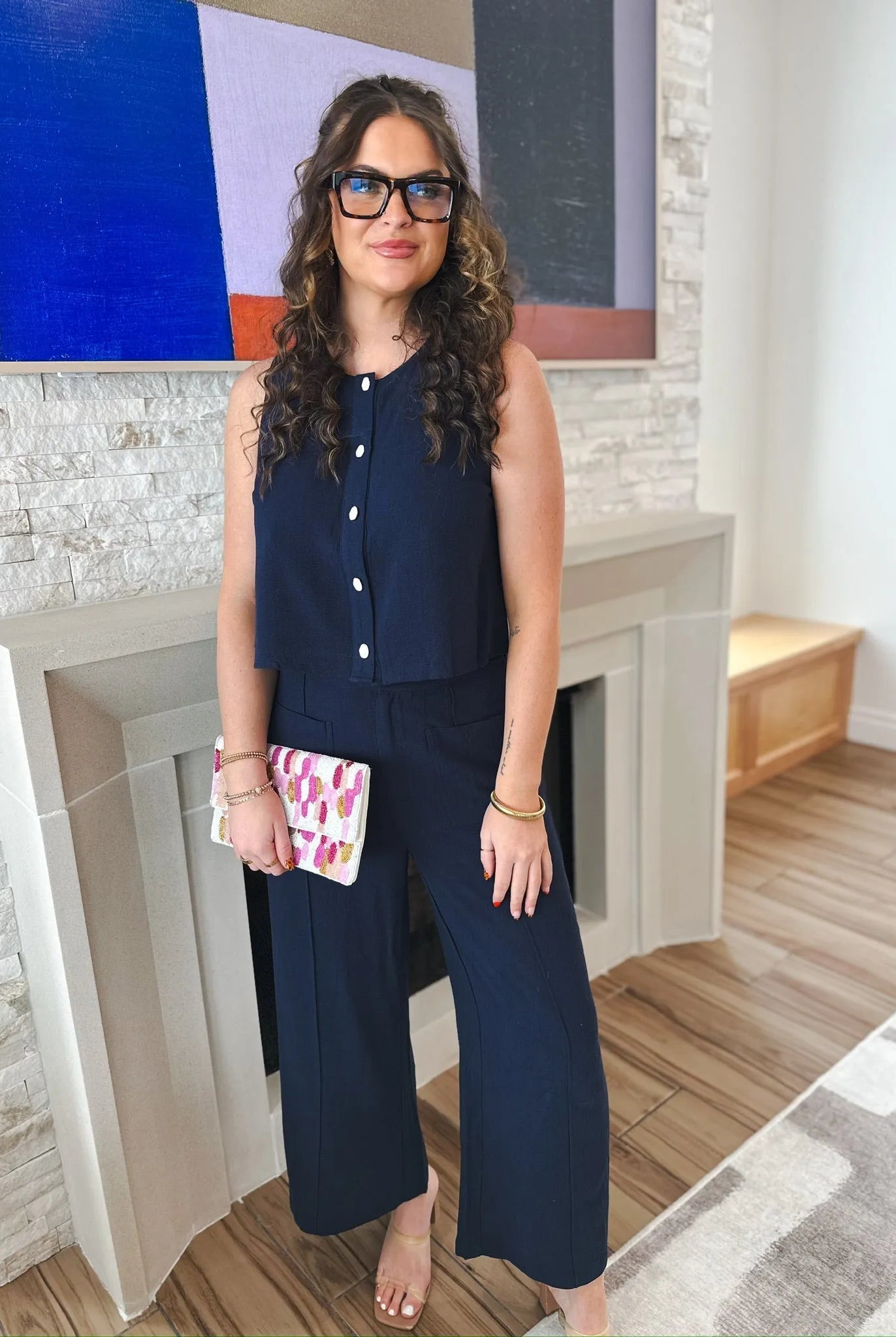 Woman wearing navy blue Entro wide-leg trousers and a matching cropped sleeveless top with white buttons, holding a