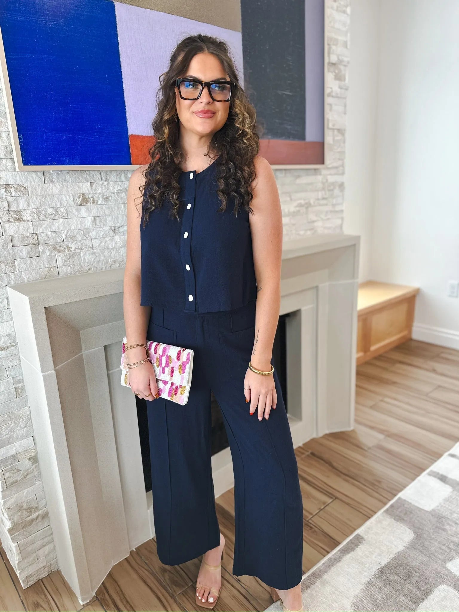 Woman wearing navy blue Entro wide-leg trousers and a matching cropped sleeveless top with white buttons, holding a