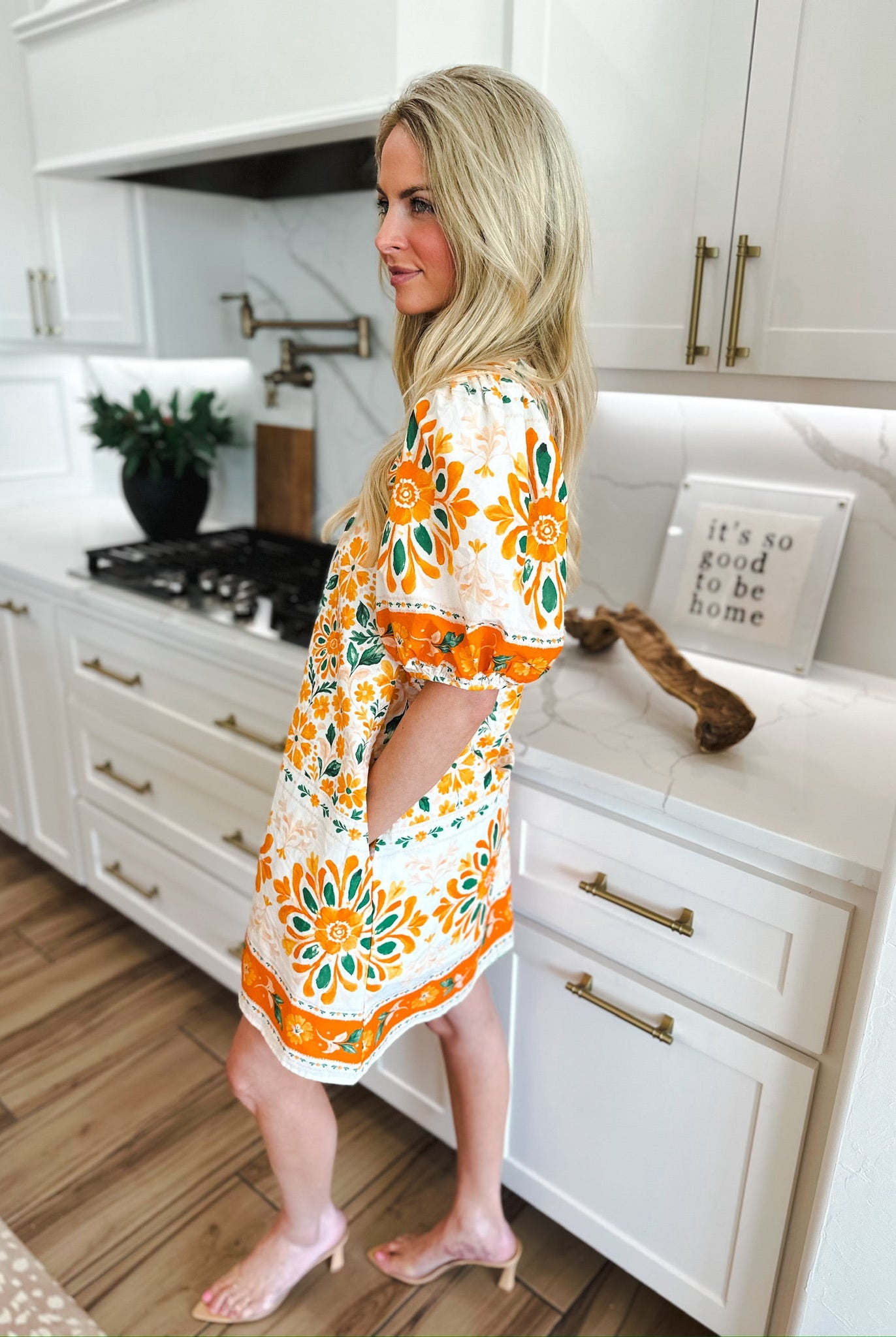 Entro orange floral puff sleeve mini dress with pockets, white base, orange and green floral print, ruffled hem, on a woman