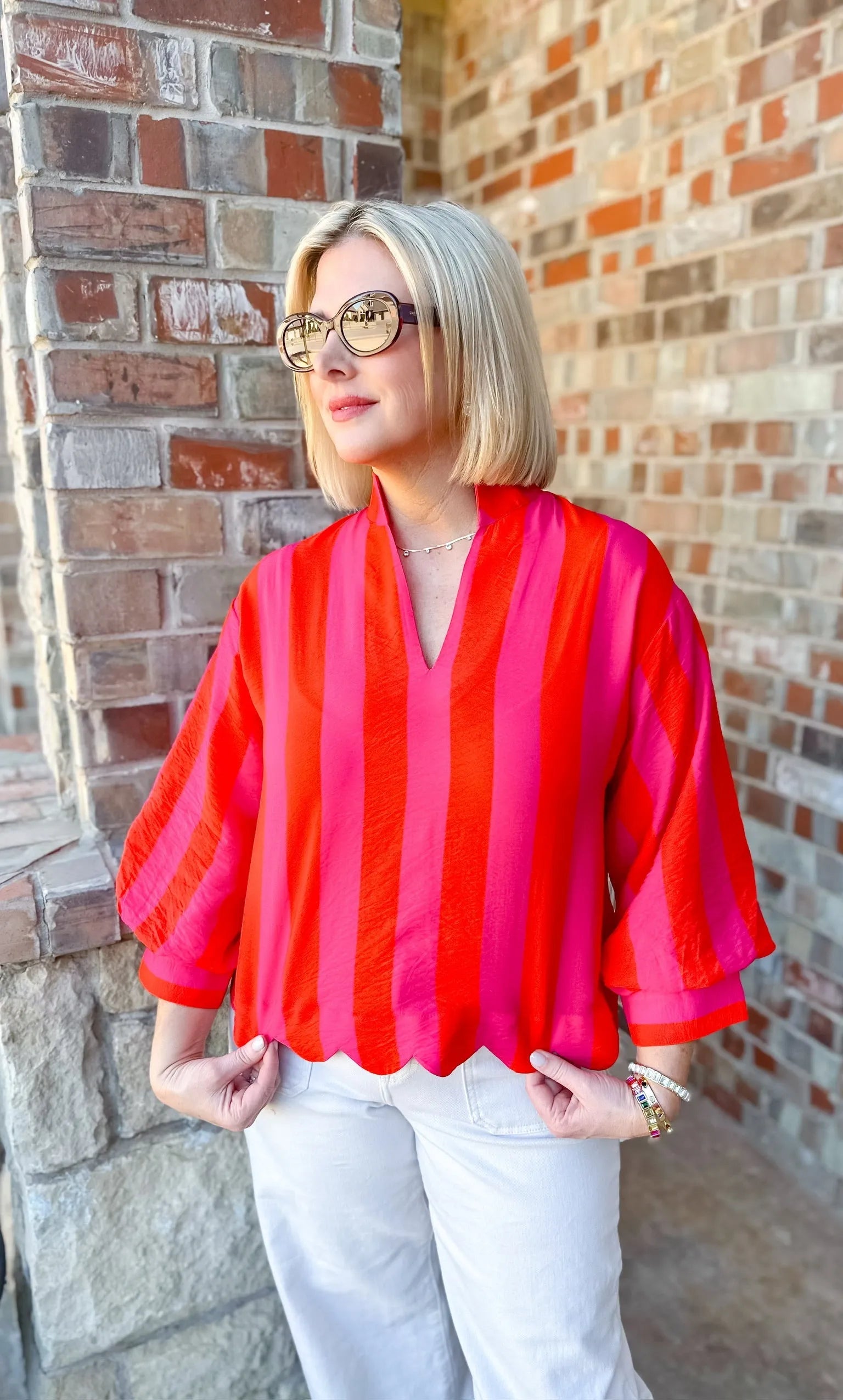 Entro pink and red striped 3/4 sleeve blouse with scalloped hem, worn by a woman with blonde hair and sunglasses.