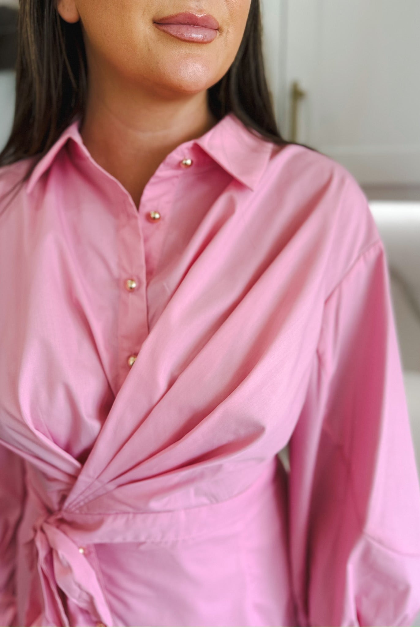 Entro pink dress with gold buttons, collared neckline, draped front, and tie waist detail. Puff sleeves visible.