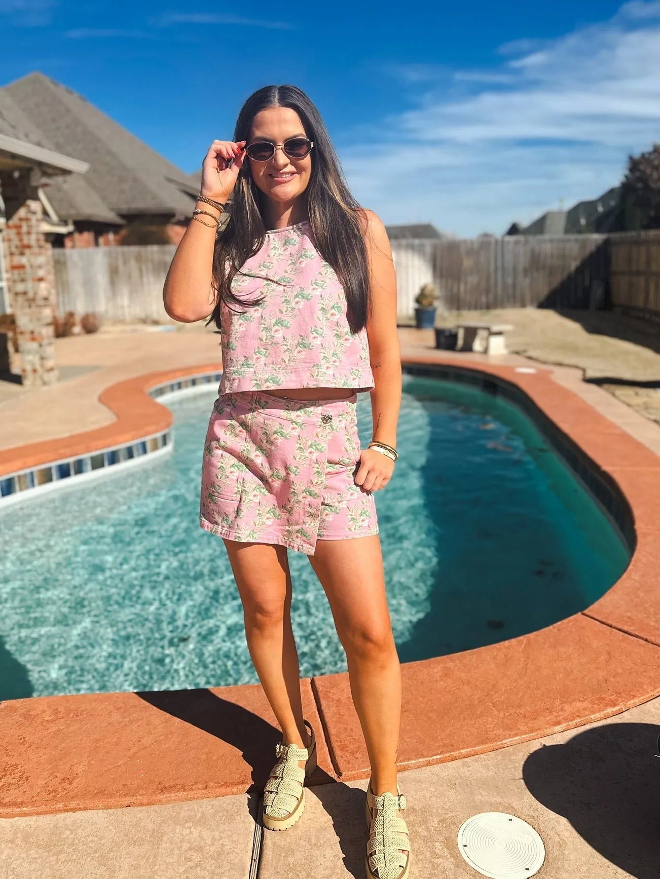 Woman wearing a pink floral print denim skort and matching halter tank top by a pool.