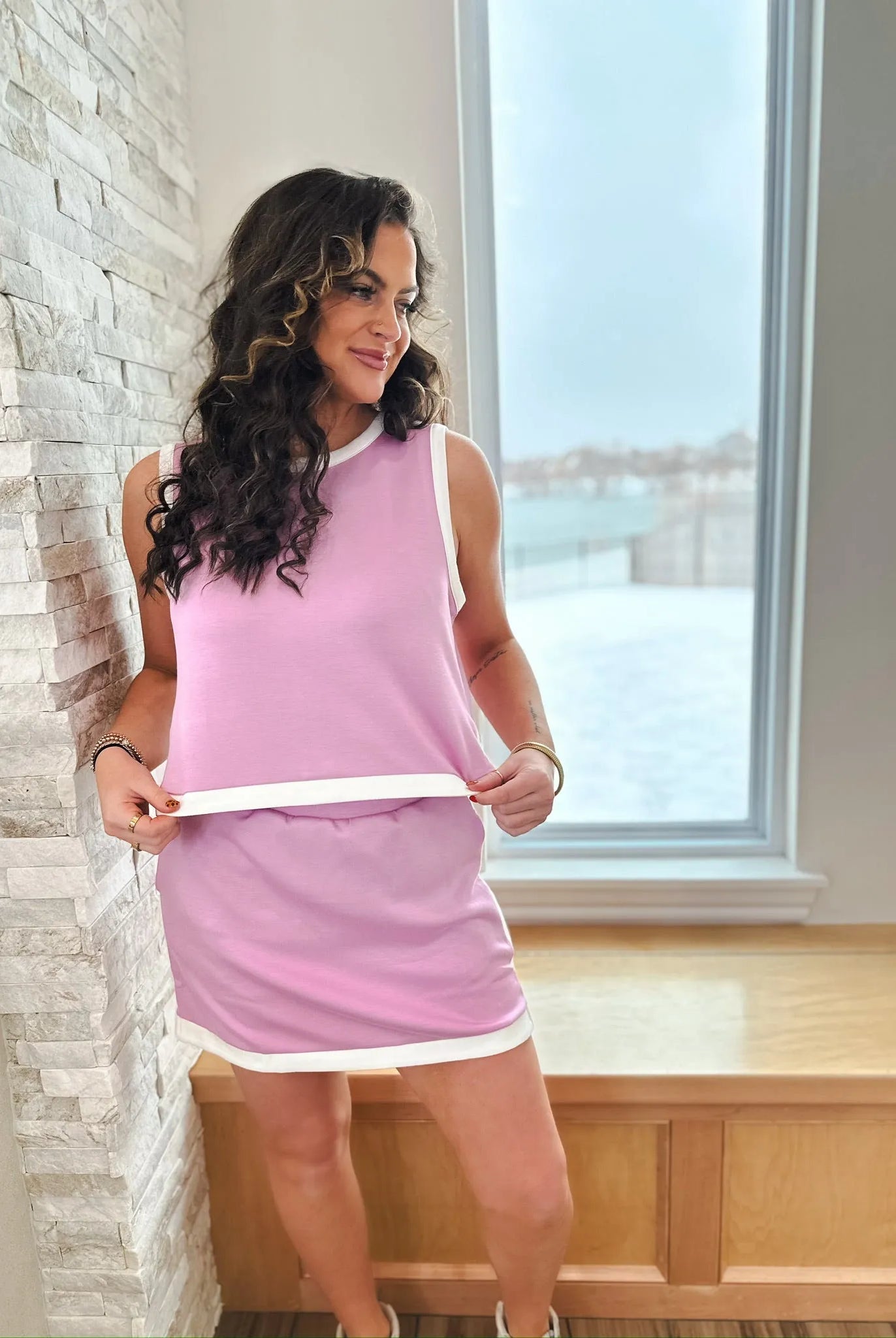 Entro women's pink sleeveless tank top and matching skirt set with white trim. Model is wearing the set by a window.