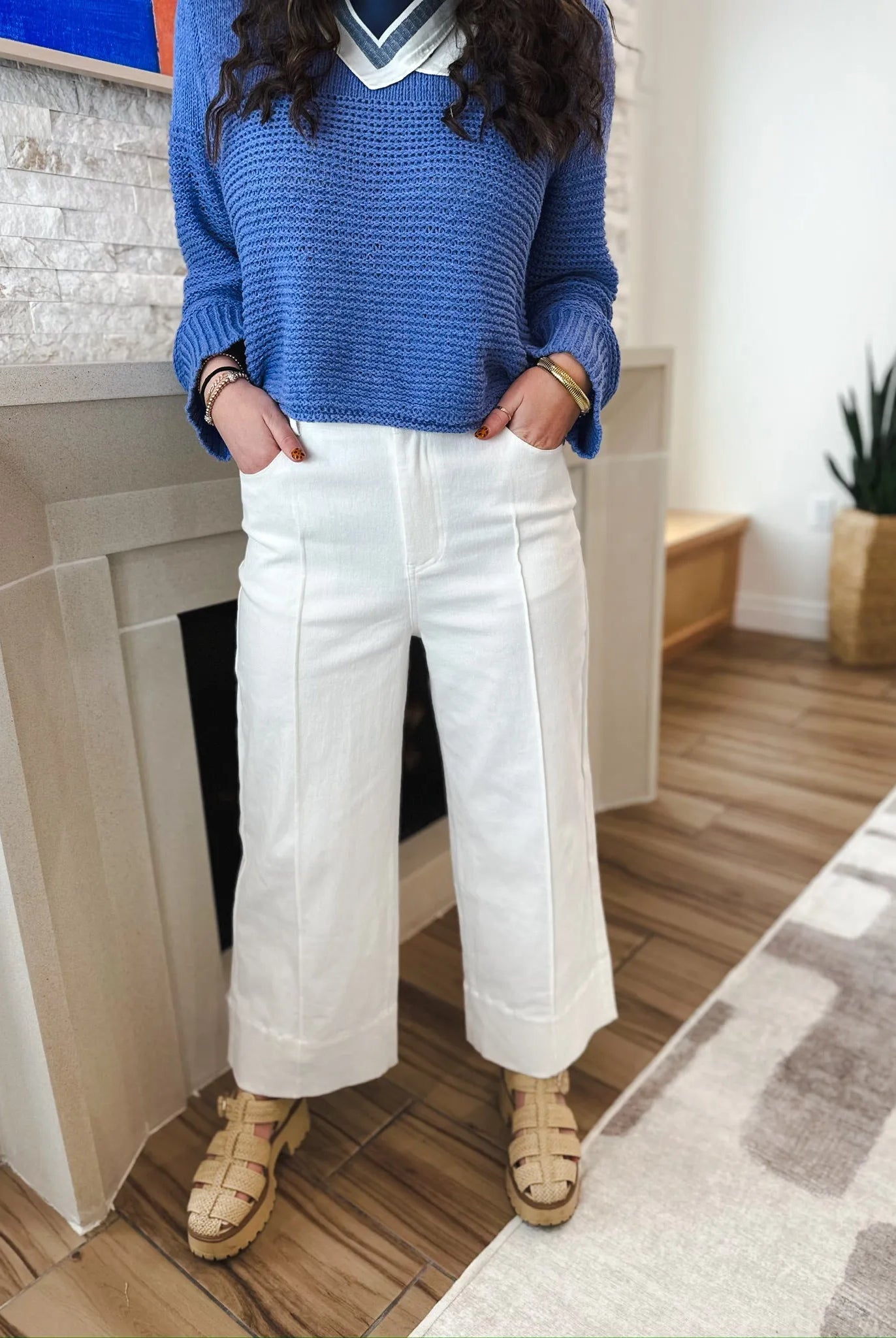 Entro white denim wide leg pleated jeans, high-waisted with a relaxed fit. Model wears blue sweater and tan sandals.