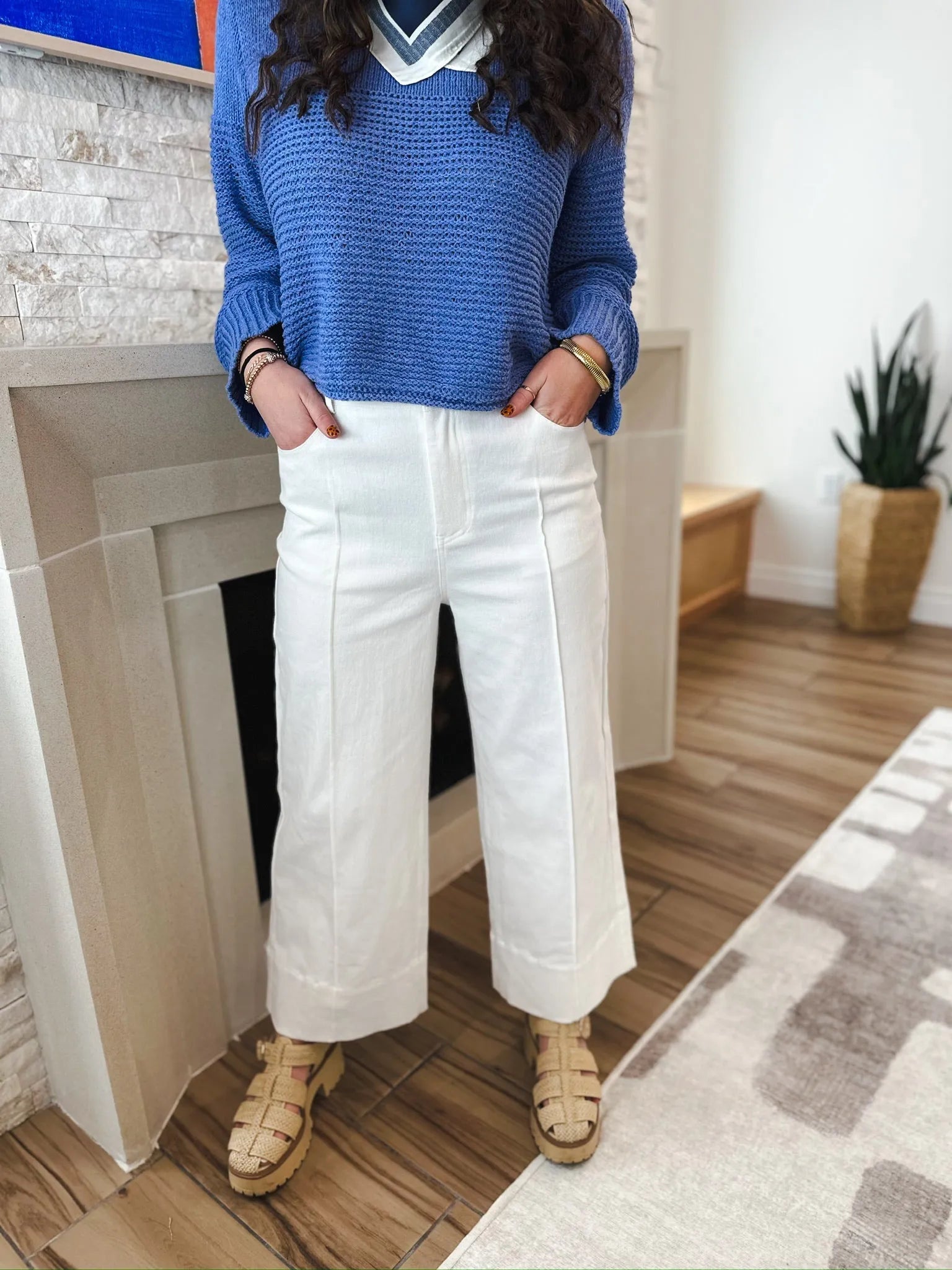 Entro white denim wide leg pleated jeans, high-waisted with a relaxed fit. Model wears blue sweater and tan sandals.