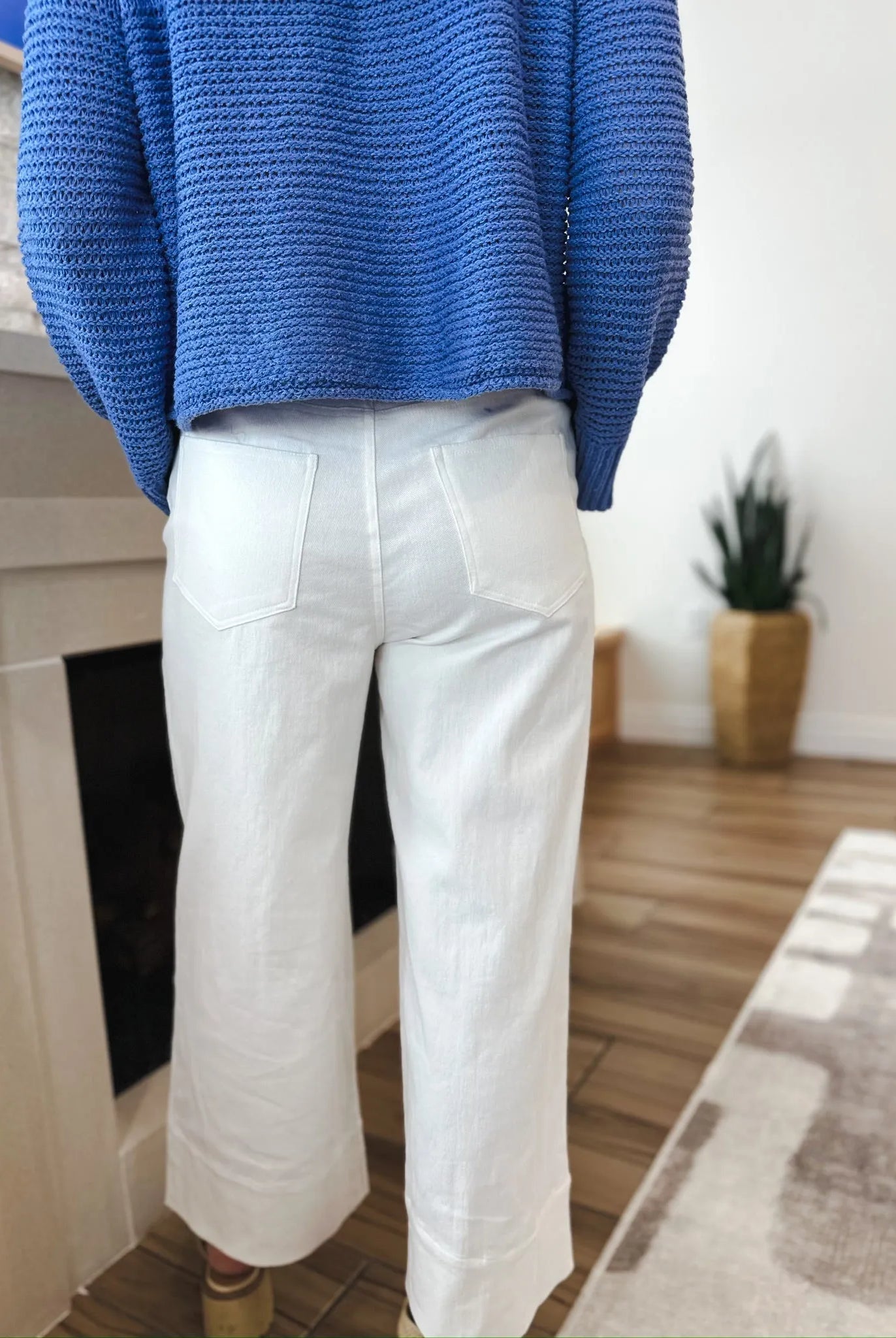 Back view of a person wearing Entro white denim wide-leg pleated jeans and a blue sweater.