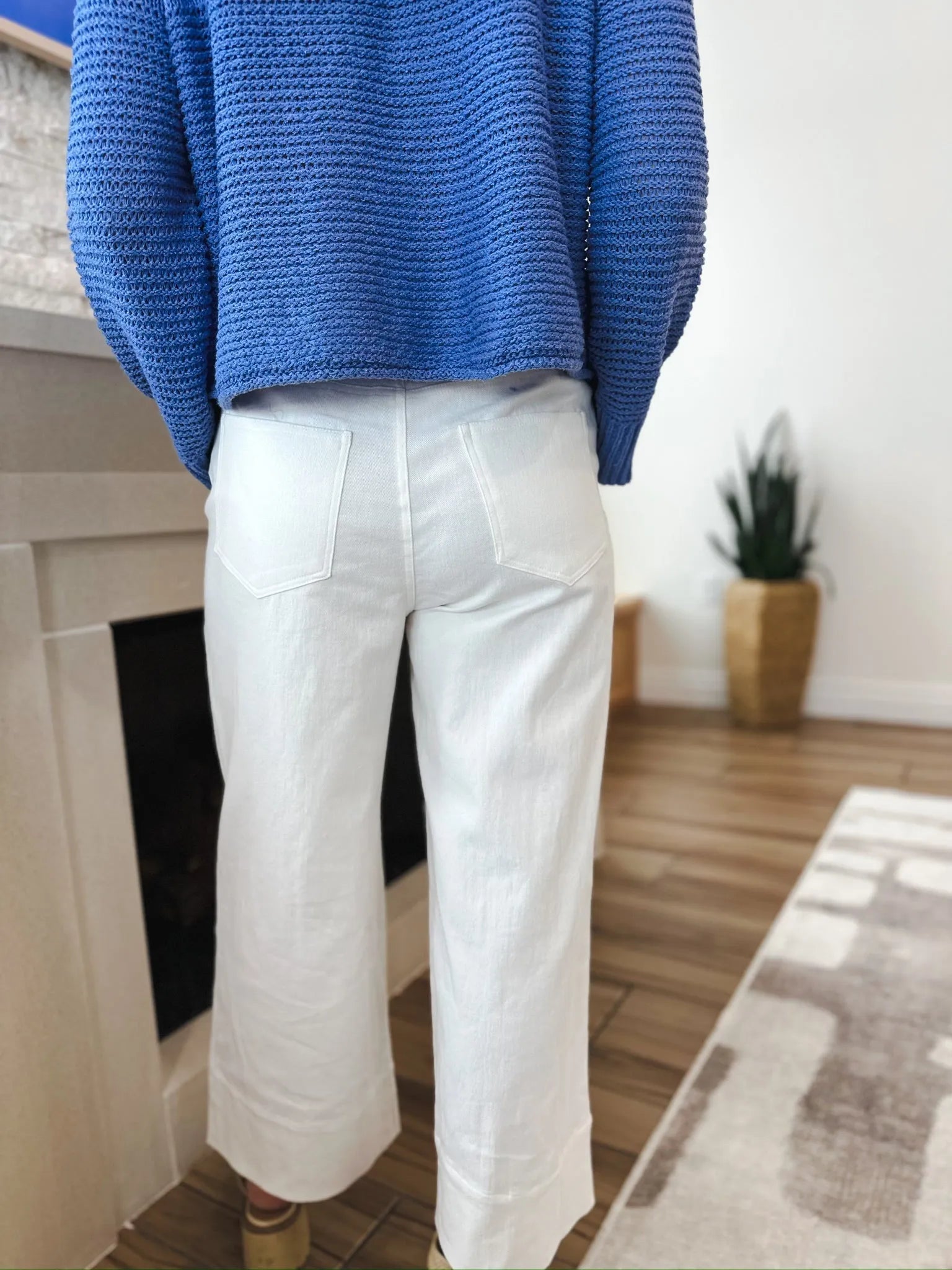 Back view of a person wearing Entro white denim wide-leg pleated jeans and a blue sweater.