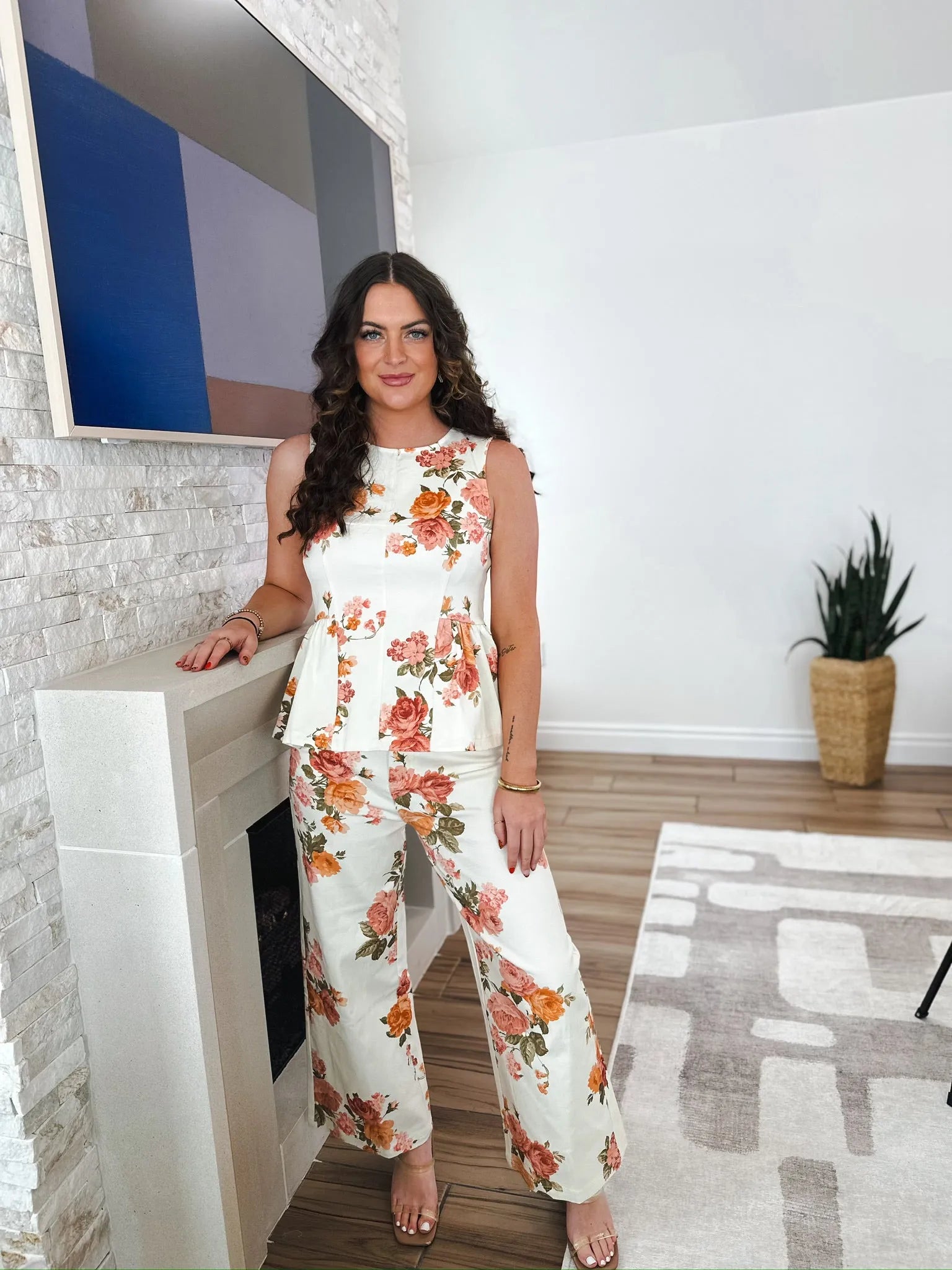 Entro white floral wide leg jeans. Woman wears a sleeveless peplum top and matching wide leg pants with a vibrant floral