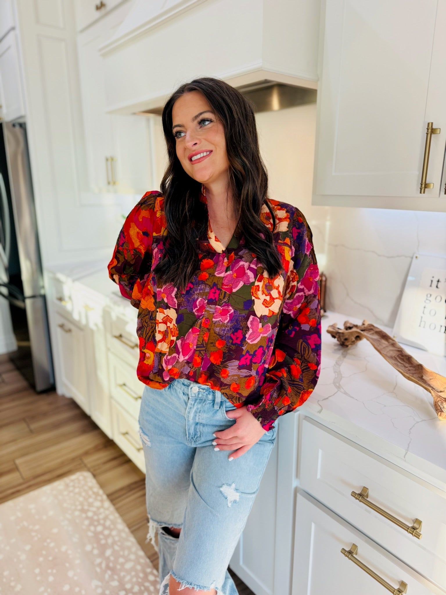 Fate multi-color floral print ruffled v-neck blouse with long sleeves, paired with light wash distressed denim jeans.