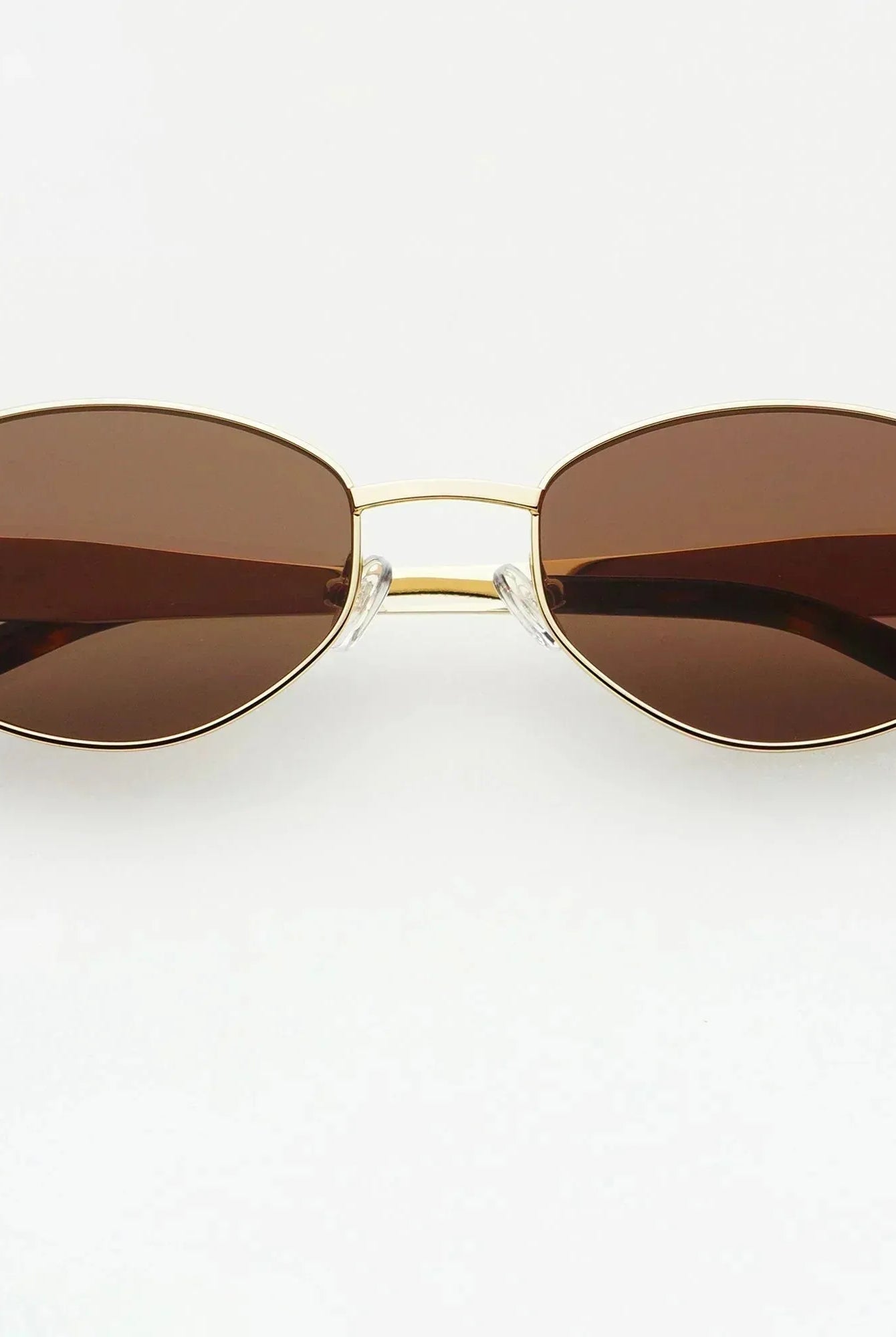 Freyrs Soho small oval sunglasses with gold frame and brown lenses. Tortoiseshell temple tips.