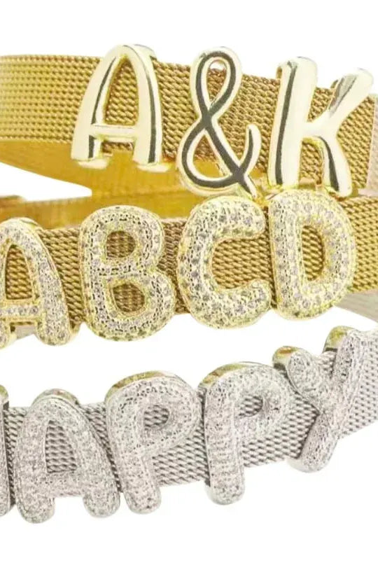Three slider bracelets: gold mesh with 'A&K' charms, gold mesh with diamond 'ABCD' charms, and silver mesh with diamond