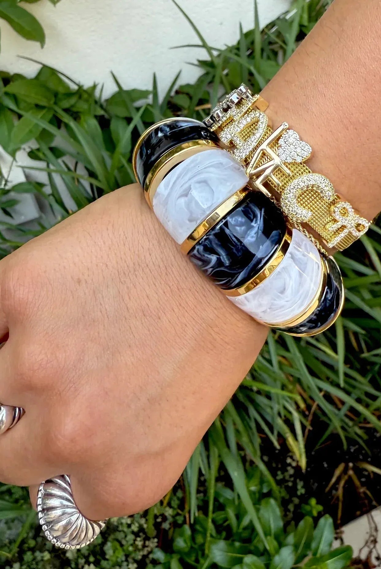 Gemelli Slider Bracelet with black, white, and gold bands. Stacked with a diamond-encrusted gold bracelet.