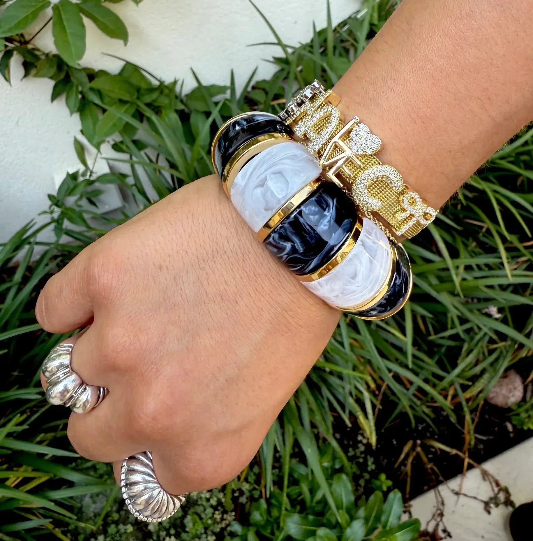 Gemelli Slider Bracelet with black, white, and gold bands. Stacked with a diamond-encrusted gold bracelet.