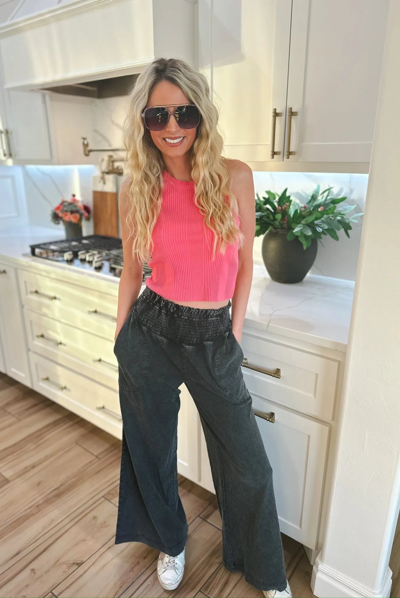 Woman wearing HyFVE black wash elastic waist wide leg trousers and a pink ribbed crop top, with sunglasses on.