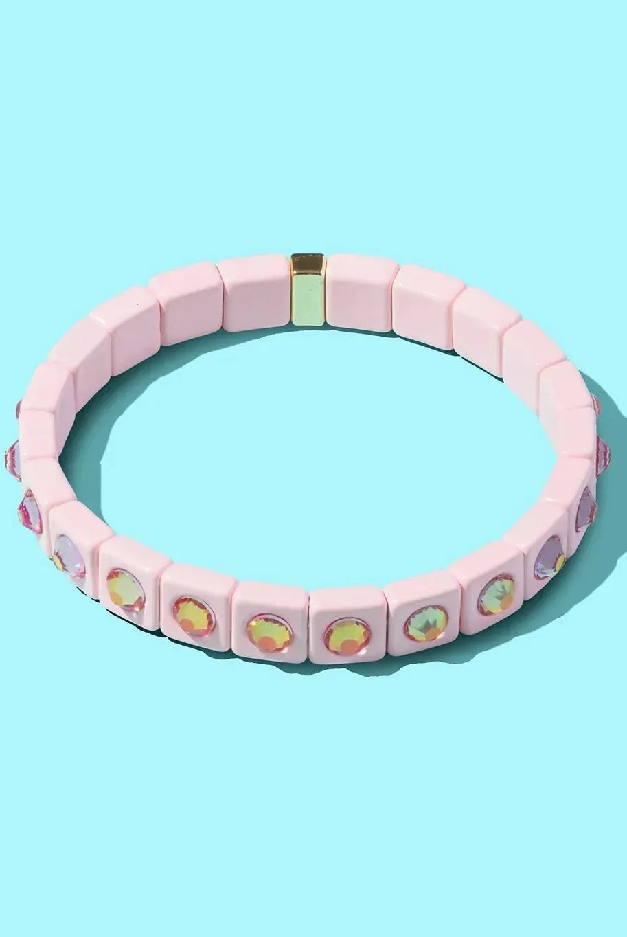 Pink enamel bracelet with square beads and iridescent stone accents on a blue background.