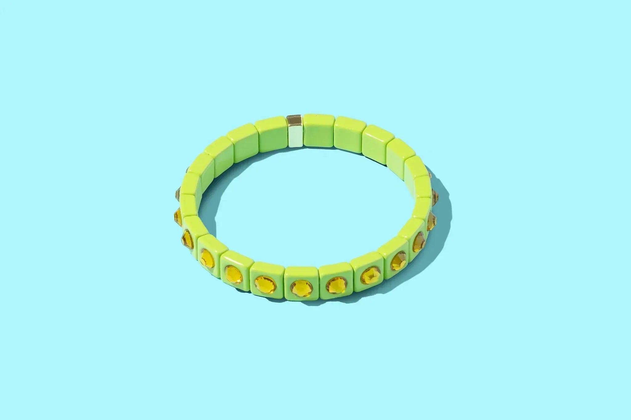 Lime green enamel bracelet with square stone accents on a light blue background.