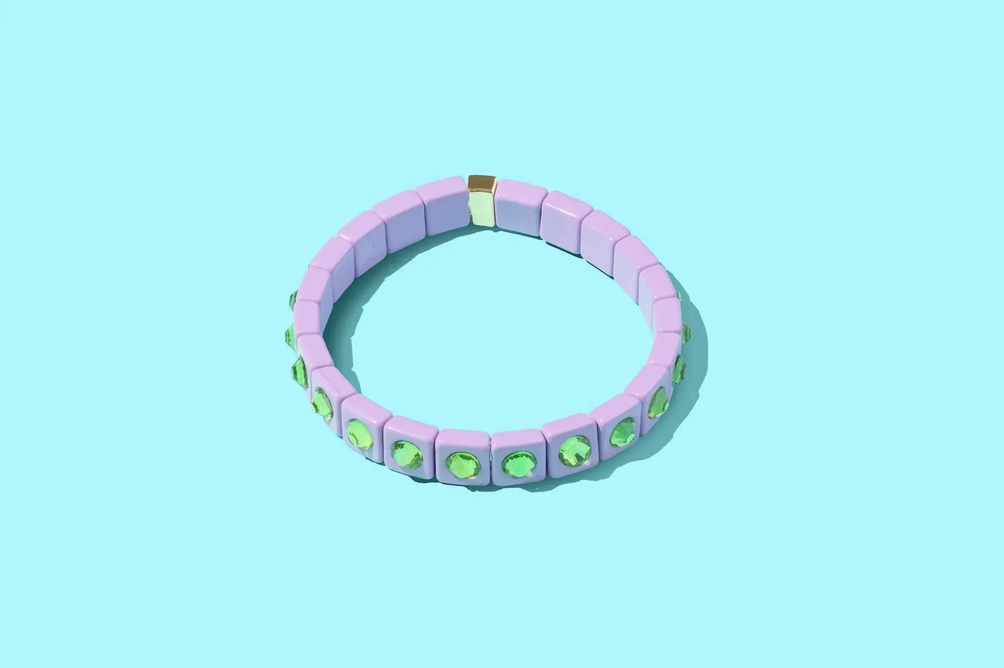 A lavender enamel bracelet with square tile beads and green square-cut stone accents, connected by a gold clasp.