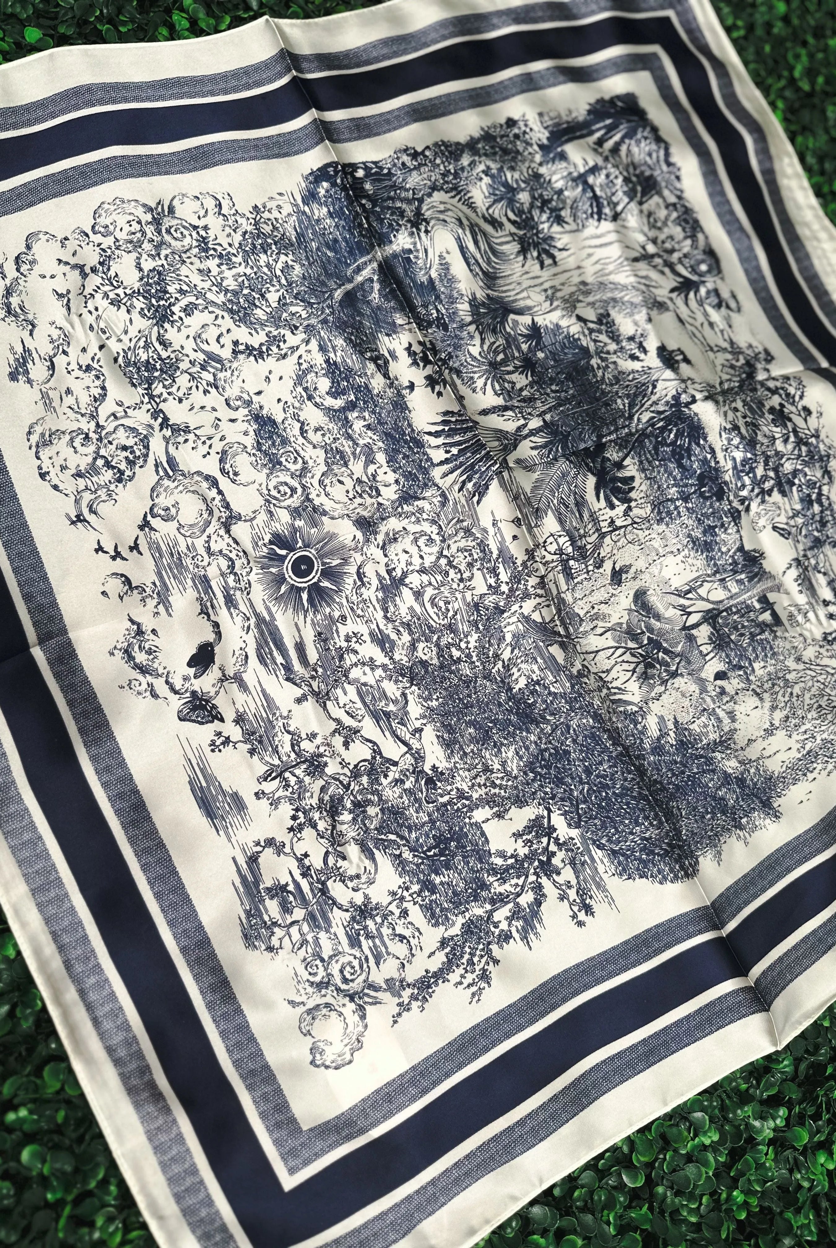 Navy and white toile print silk neck scarf with a detailed landscape scene and striped border.