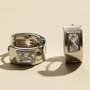 Nickel and Suede silver baguette huggie earrings with clear gemstone inlay. Detailed shot showcasing the polished metal and