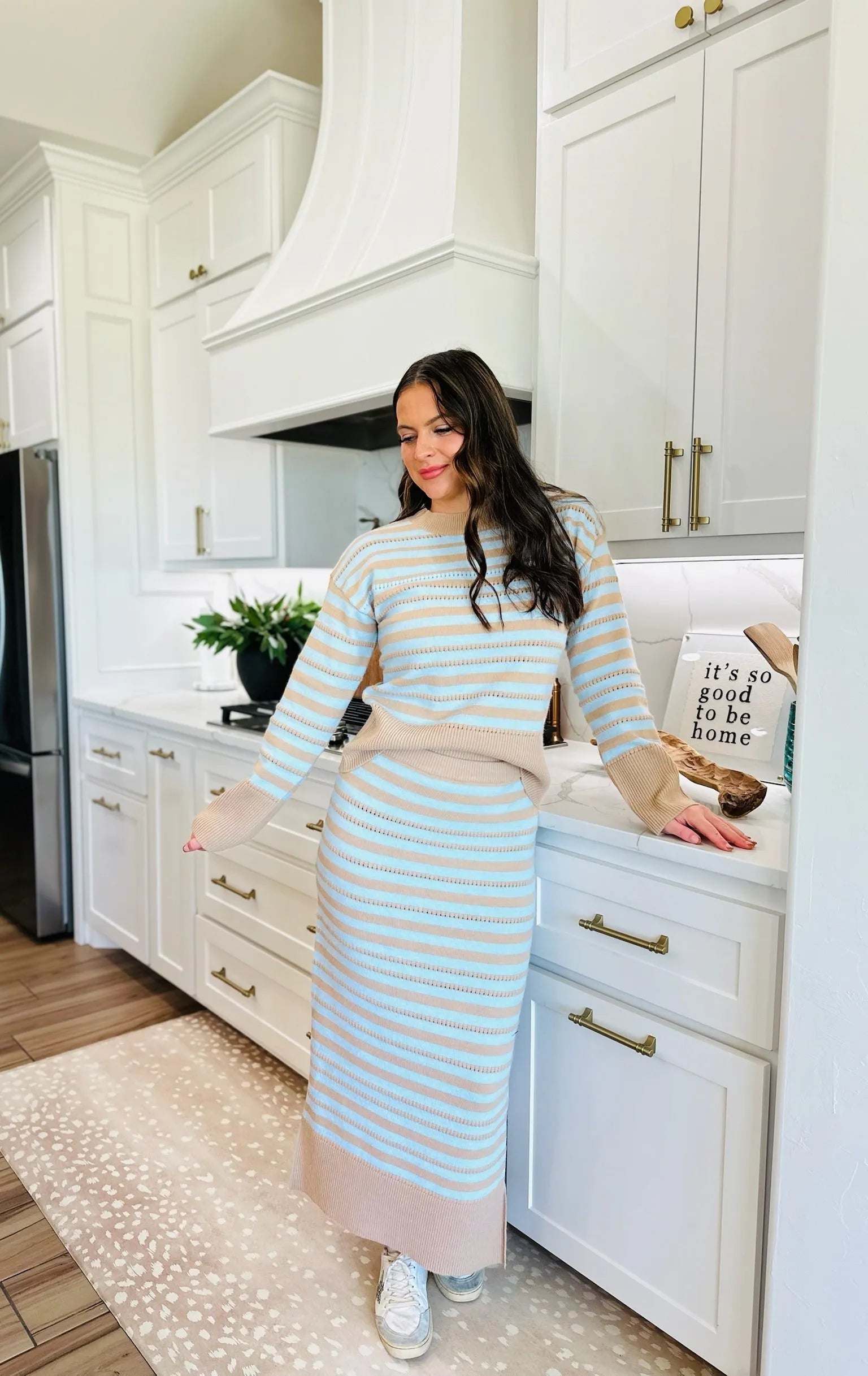 Oatmeal and blue striped knit sweater and matching midi skirt set worn by a woman in a modern kitchen.