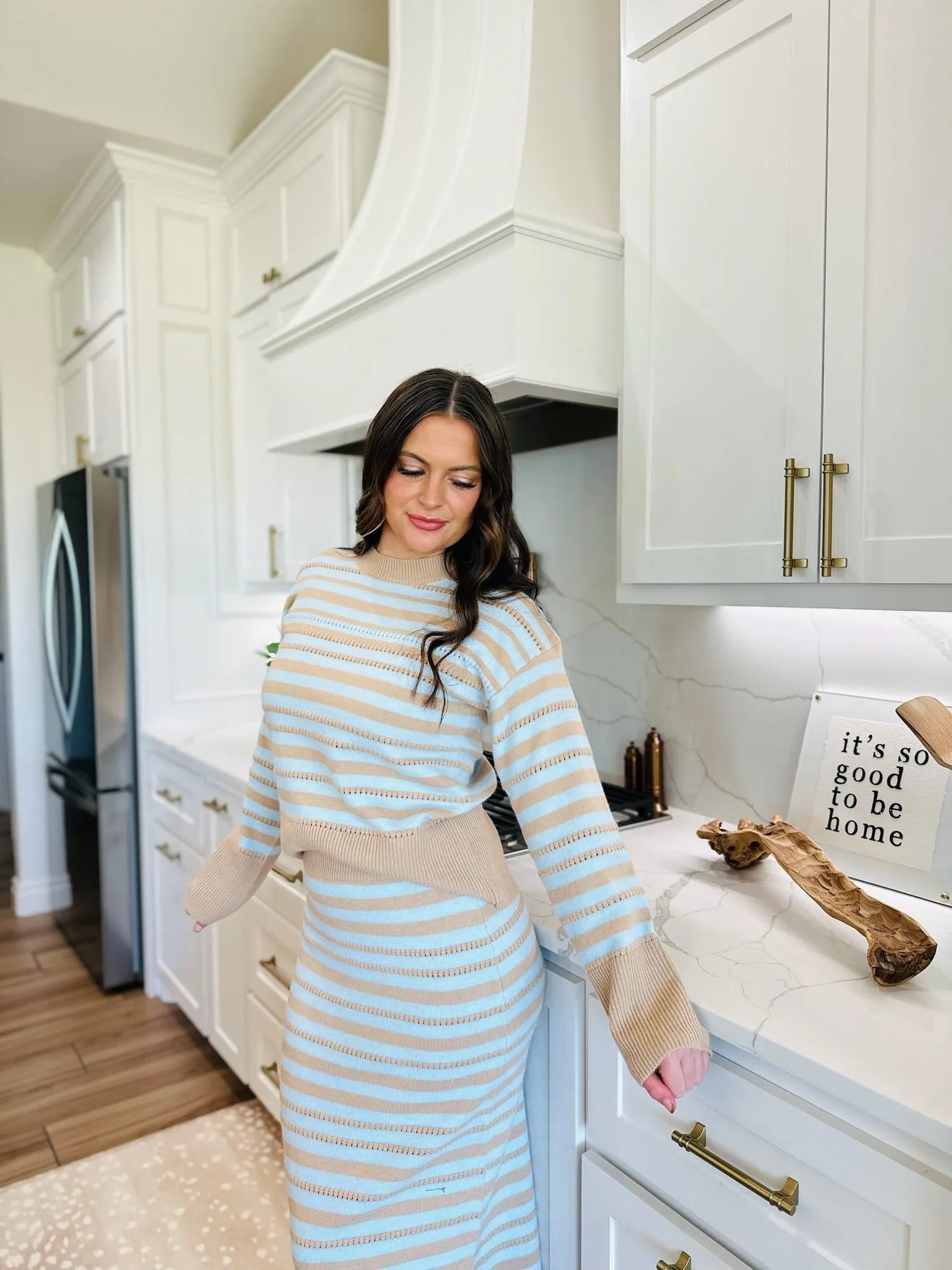 Woman in oatmeal and blue striped sweater and matching skirt set, knit texture, cropped sweater, midi skirt, kitchen setting.