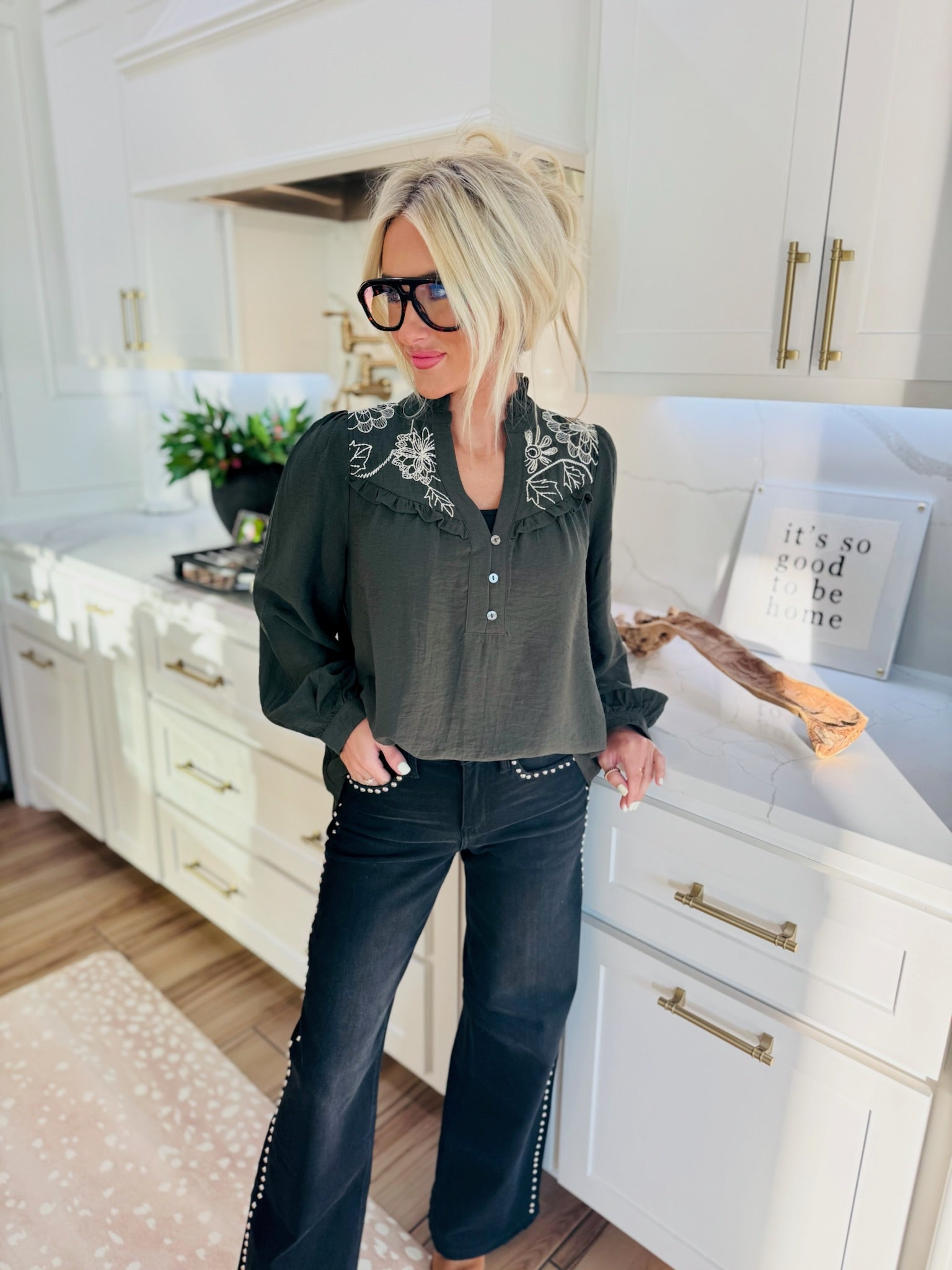 Dark olive green blouse with white floral embroidery on the collar and shoulders. The blouse has a button-up front and