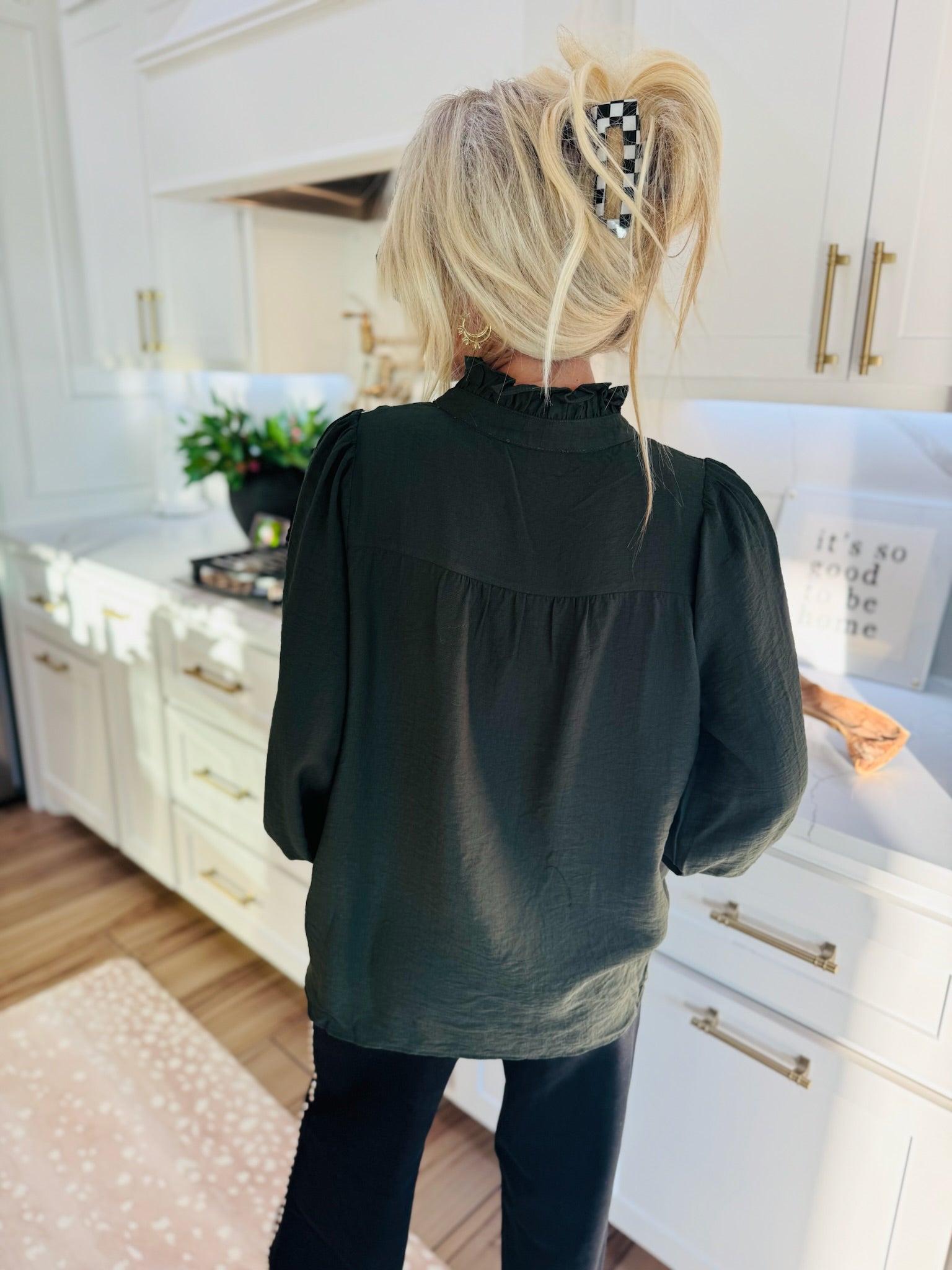 Dark olive green blouse with ruffled collar, puffed shoulders, and long sleeves. Back view of woman wearing blouse.