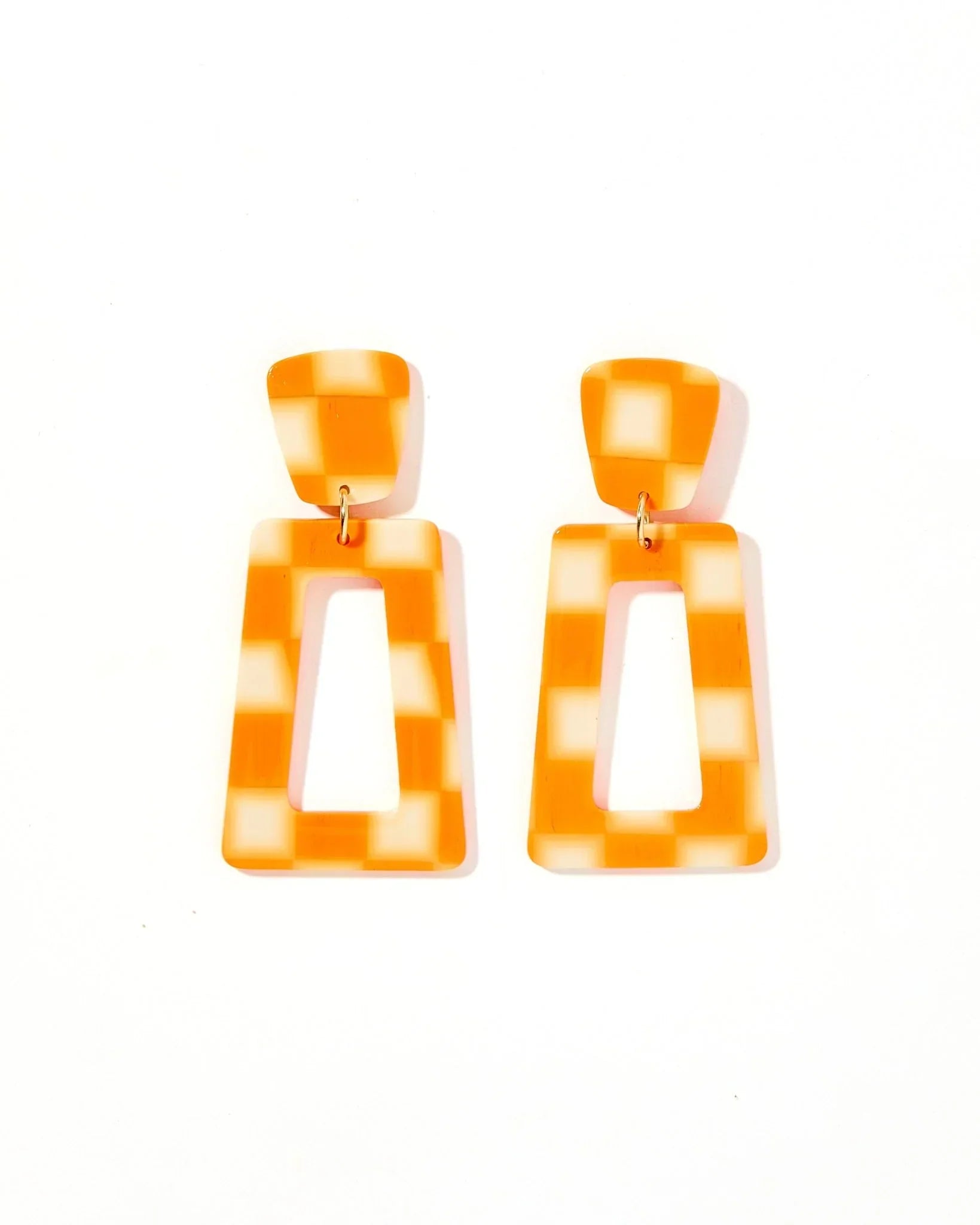 Orange and white checkered statement earrings with rectangular cut-out design. Modern dangle style.