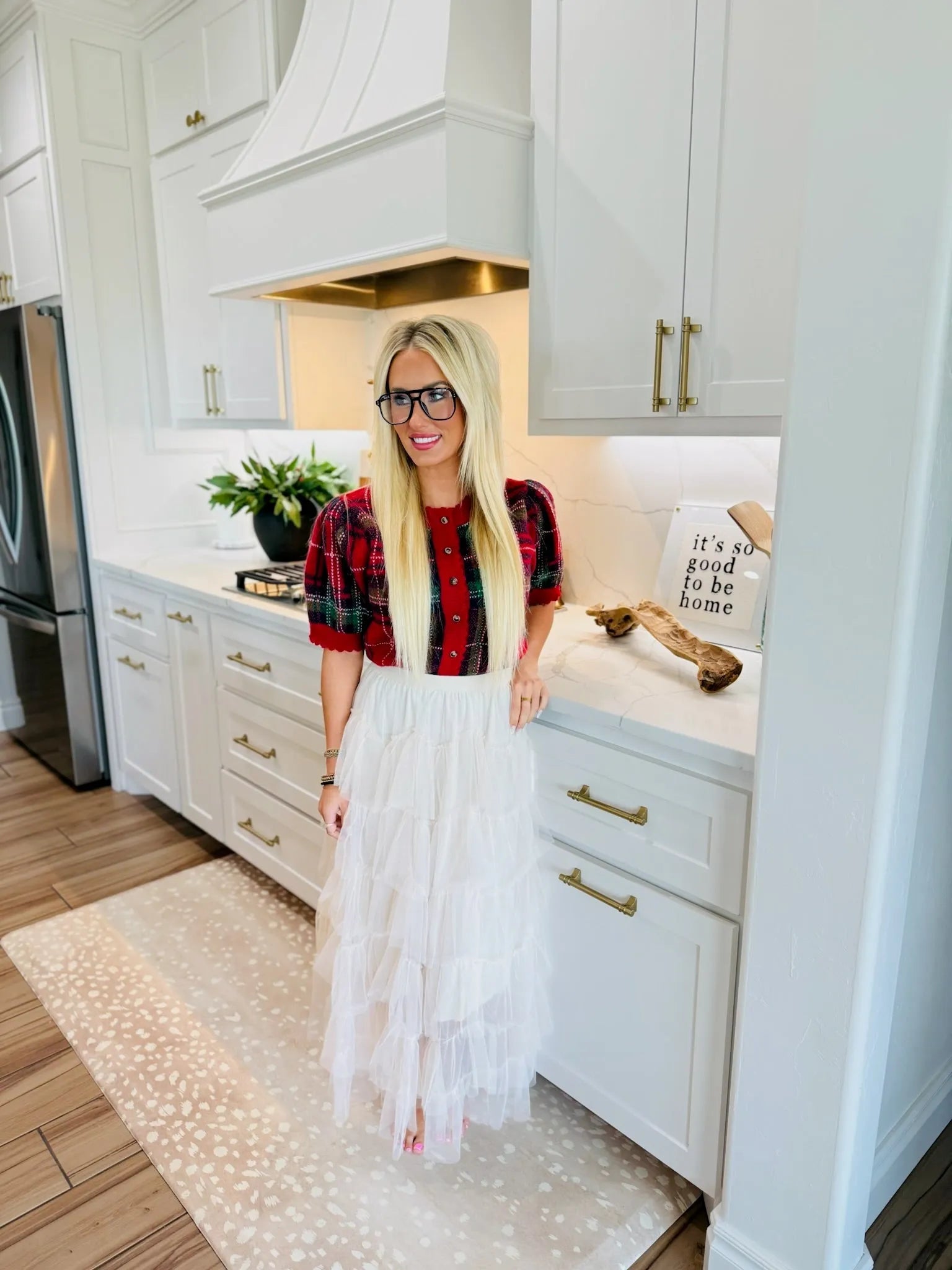 Woman wearing a white tiered ruffle midi skirt and a red plaid top in a kitchen.