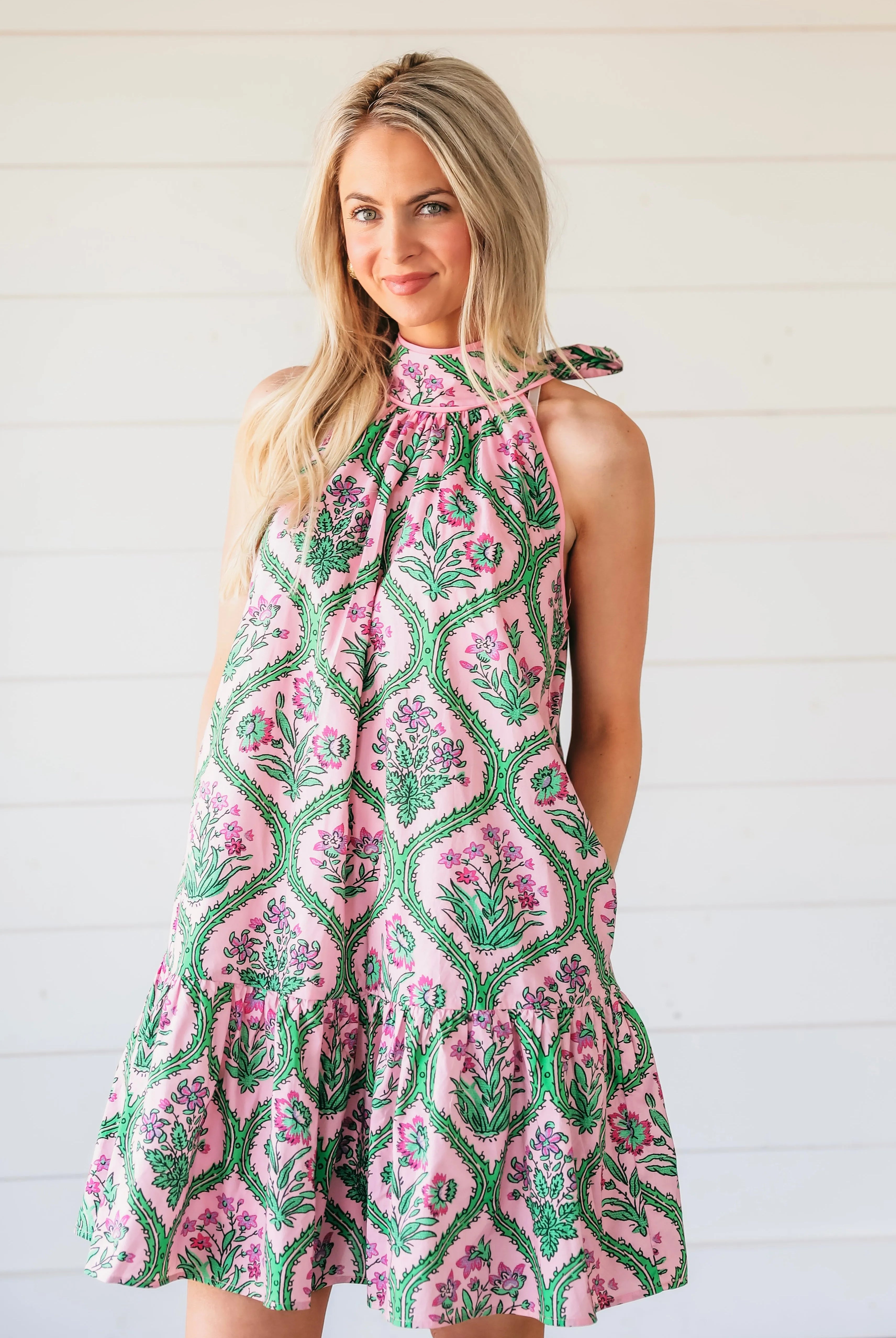 Pink floral halter mini dress with green vine pattern and ruffled hem.