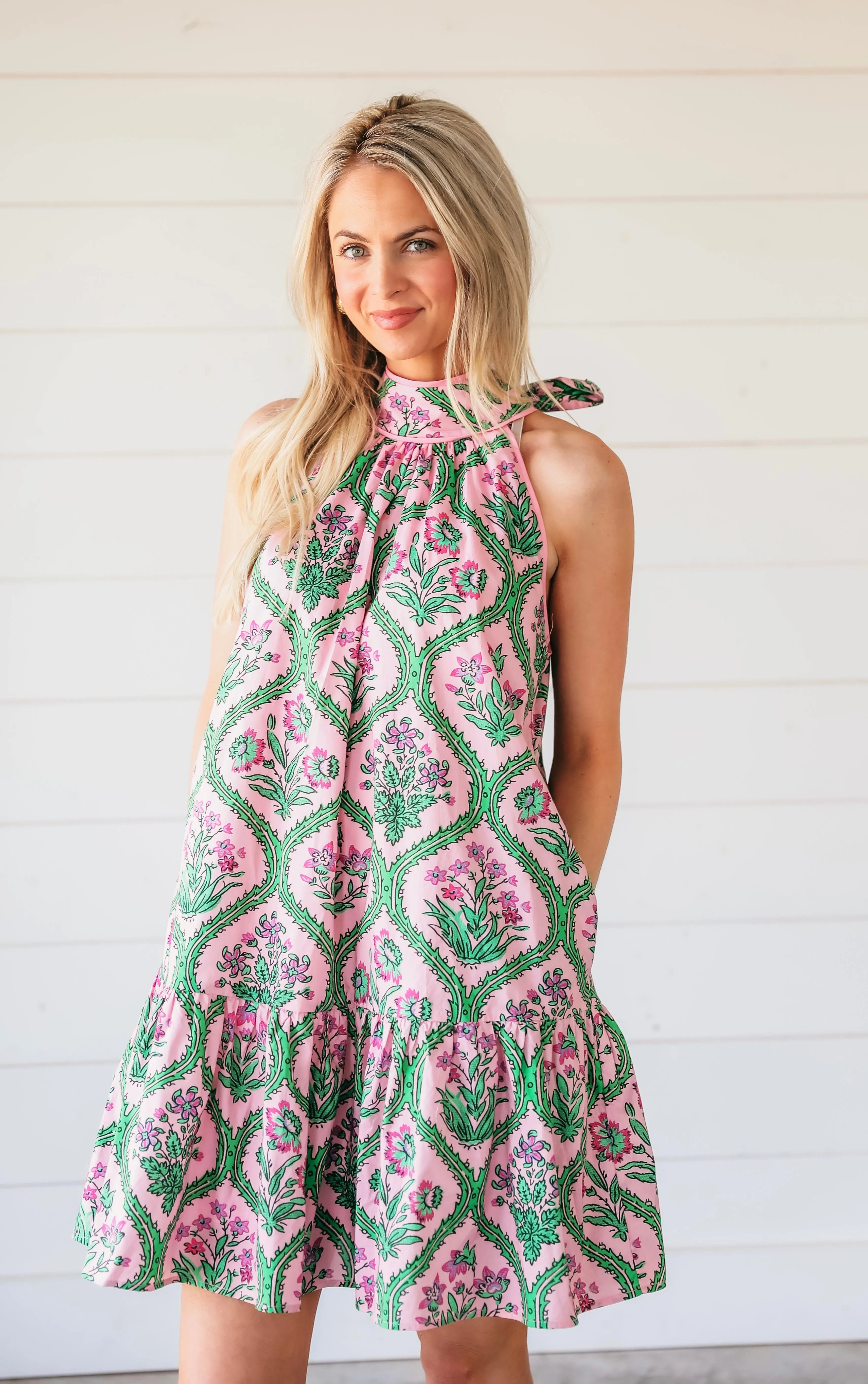 Pink floral halter mini dress with green vine pattern and ruffled hem.