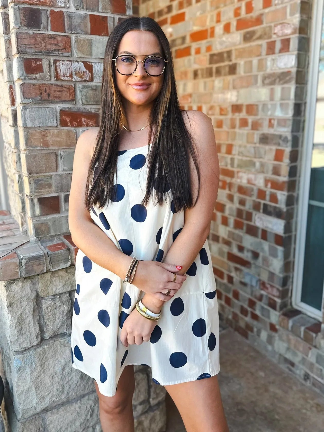 Navy and cream polka dot mini dress with back strap and bow detail. Sleeveless design.