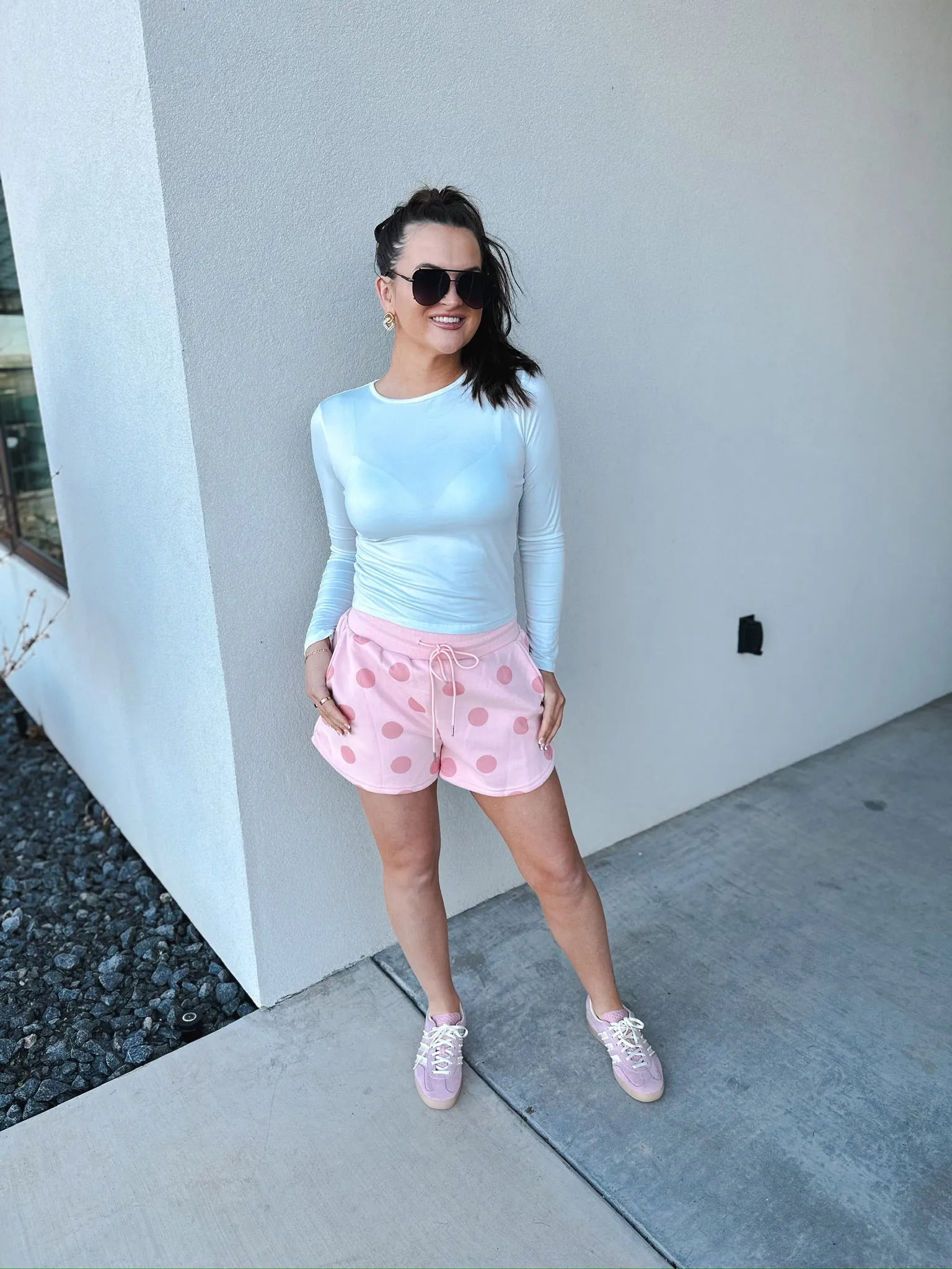Poppy & Pine blush pink polka dot shorts with a drawstring waist and cuffed hem. Woman wearing shorts with a white