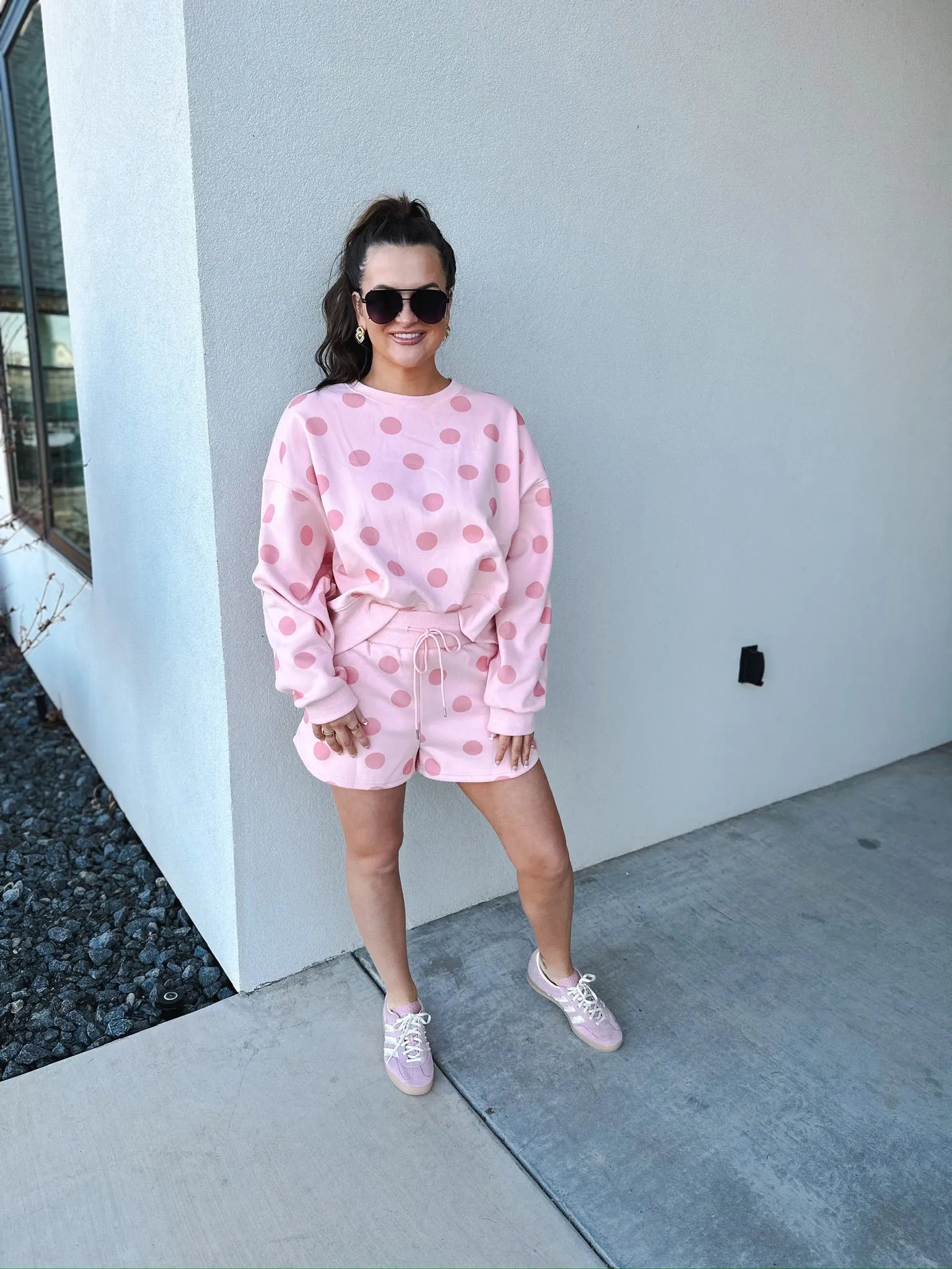 Poppy & Pine blush pink polka dot sweatshirt and matching shorts set on a woman wearing sunglasses and pink sneakers.
