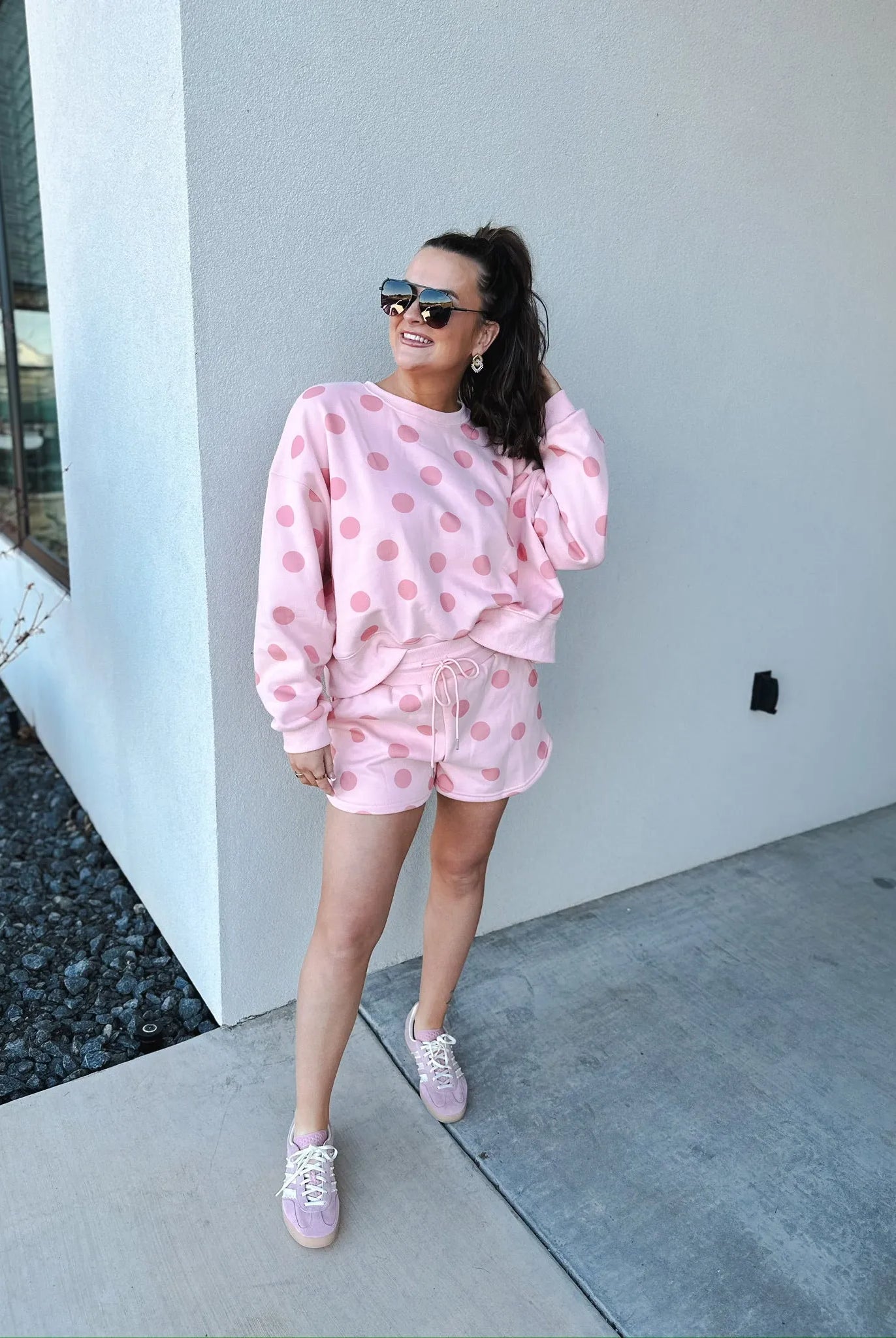 Blush pink polka dot sweatshirt and matching shorts set on a woman. Features crew neck, long sleeves, drawstring waist