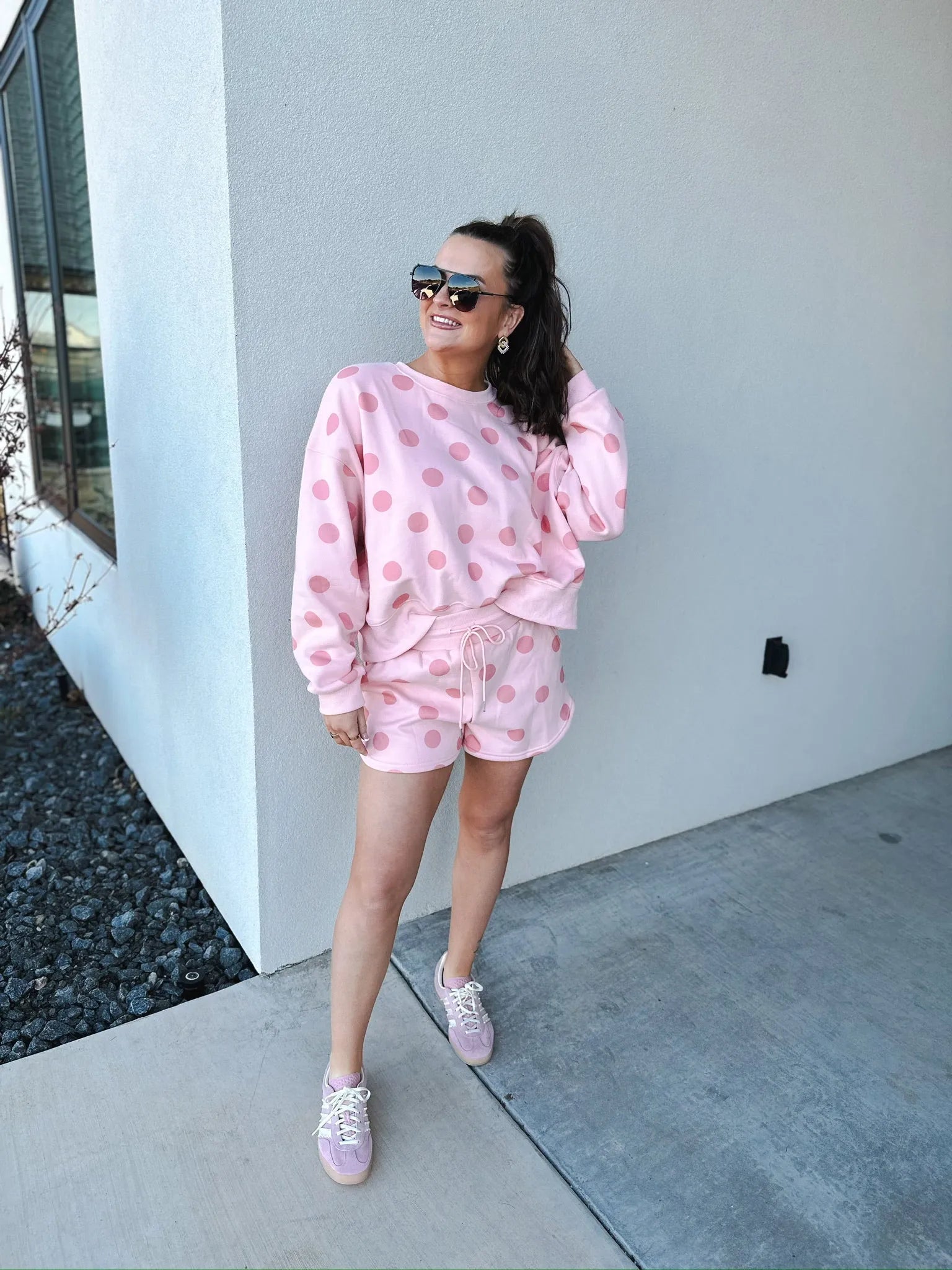 Blush pink polka dot sweatshirt and matching shorts set on a woman. Features crew neck, long sleeves, drawstring waist