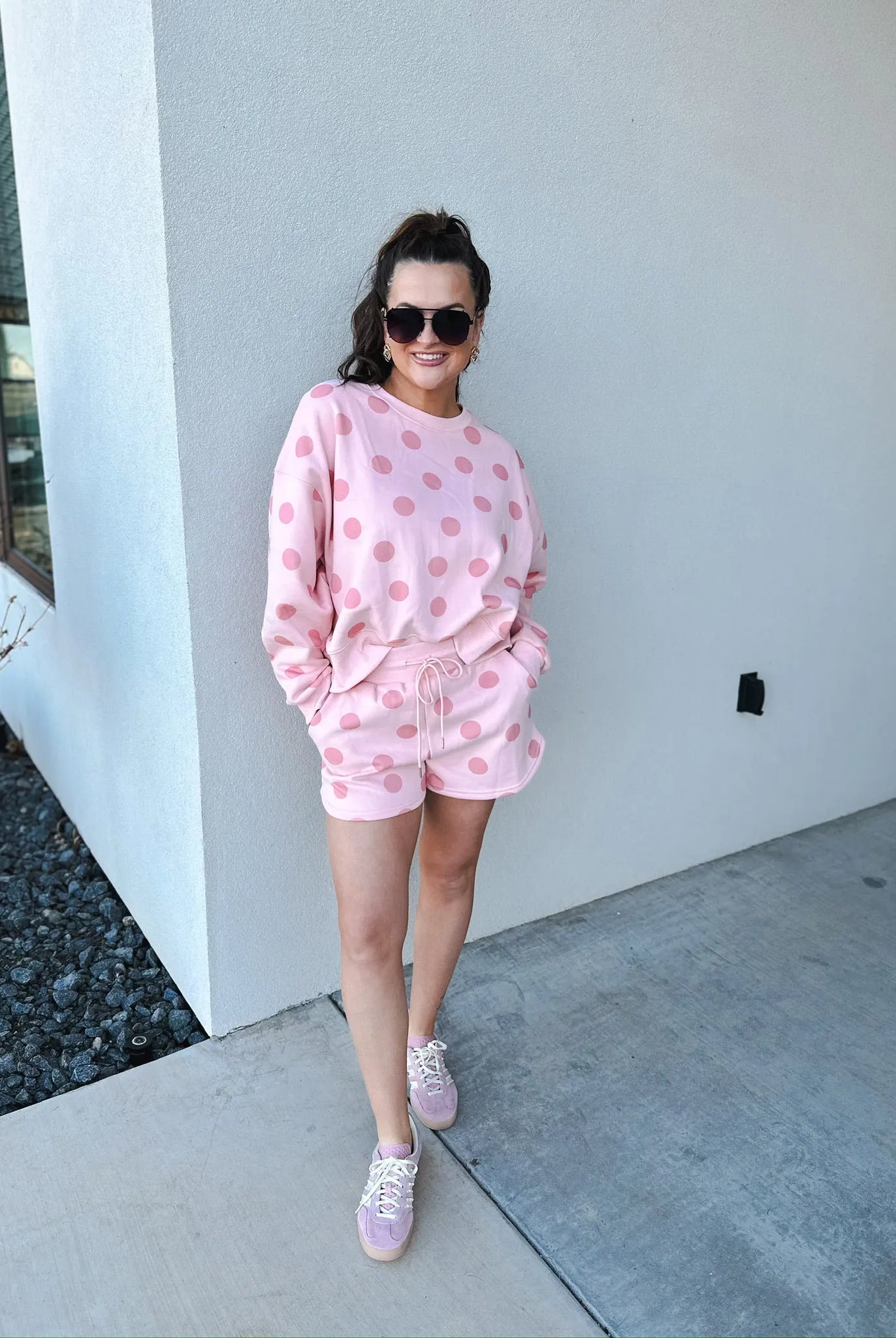 Poppy & Pine blush pink polka dot sweatshirt and matching shorts set on a woman wearing sunglasses and sneakers.
