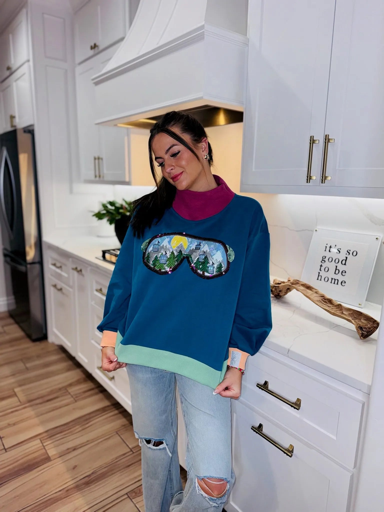 QOS Colorblock ski goggle sweatshirt with a sequined mountain and sun scene. Teal, maroon, mint, and coral colors. Includes