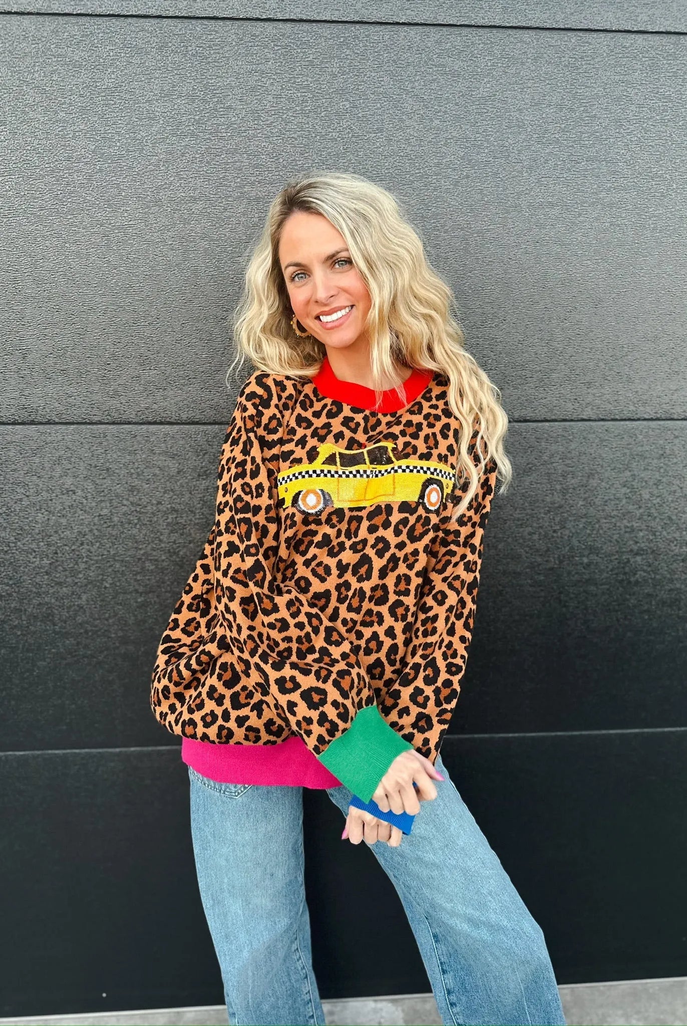 Queen of Sparkles leopard print sweater with a yellow taxi cab graphic, red collar, and colorful cuffs.